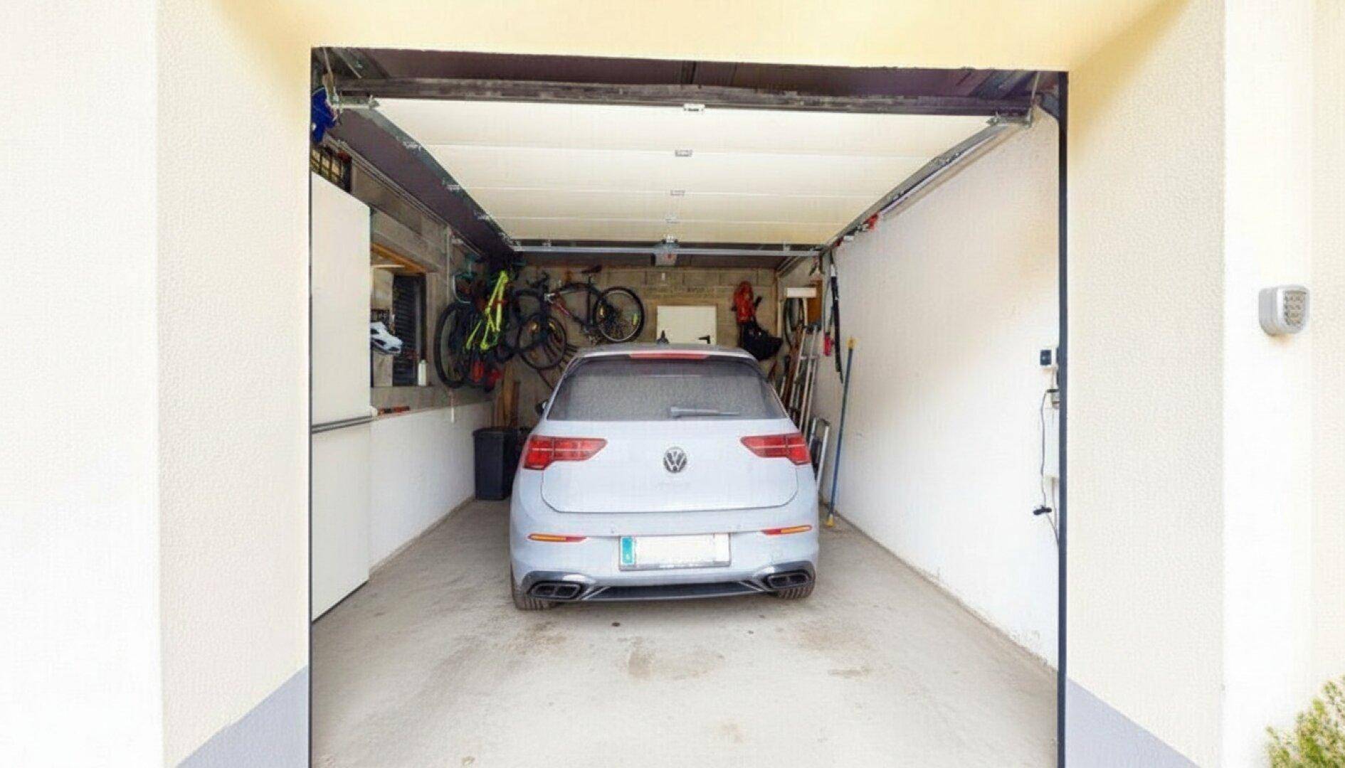 Geräumige Garage mit Platz für ein Fahrzeug und praktischer Fahrradaufhängung an der Wand.