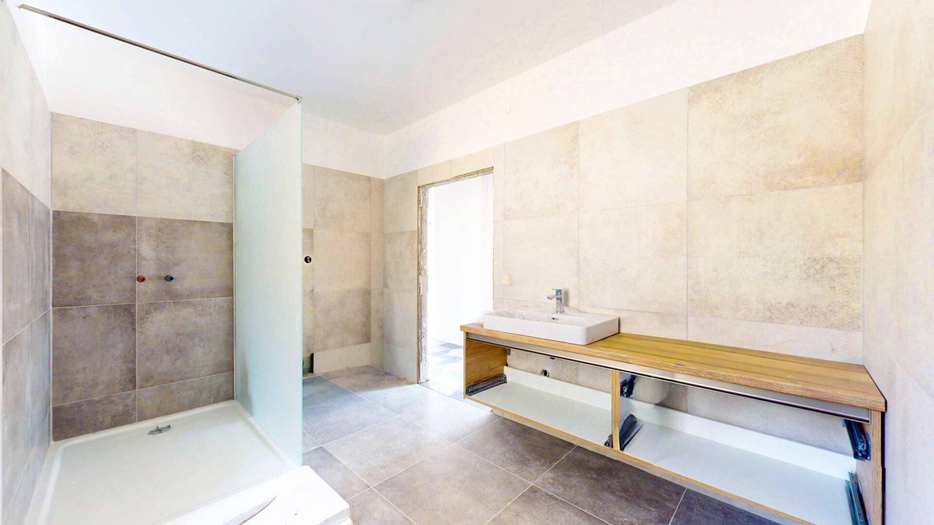 Modernes Badezimmer mit begehbarer Dusche, Einzelwaschbecken und hellen Fliesen.