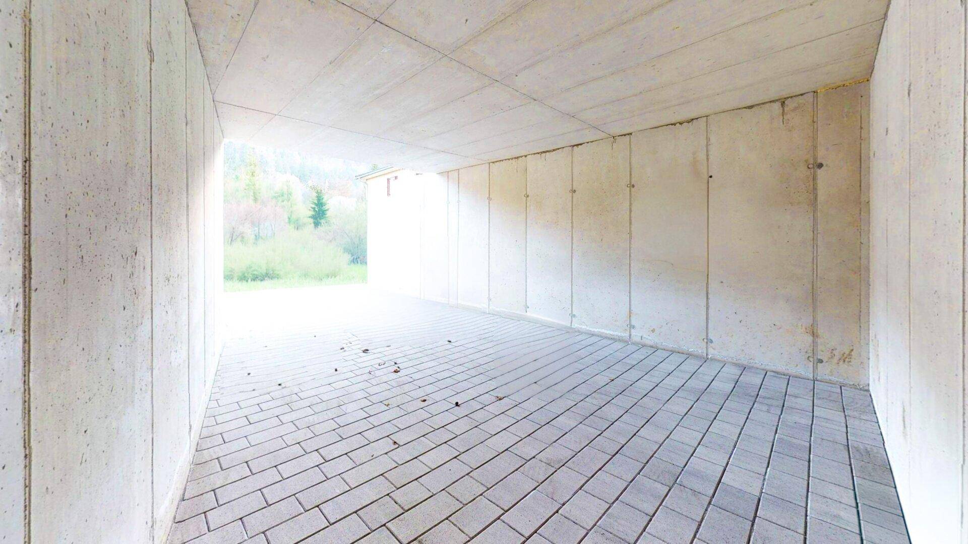 Geräumige Tiefgarage mit Betonwänden und gepflastertem Boden, bietet sicheren Stellplatz.