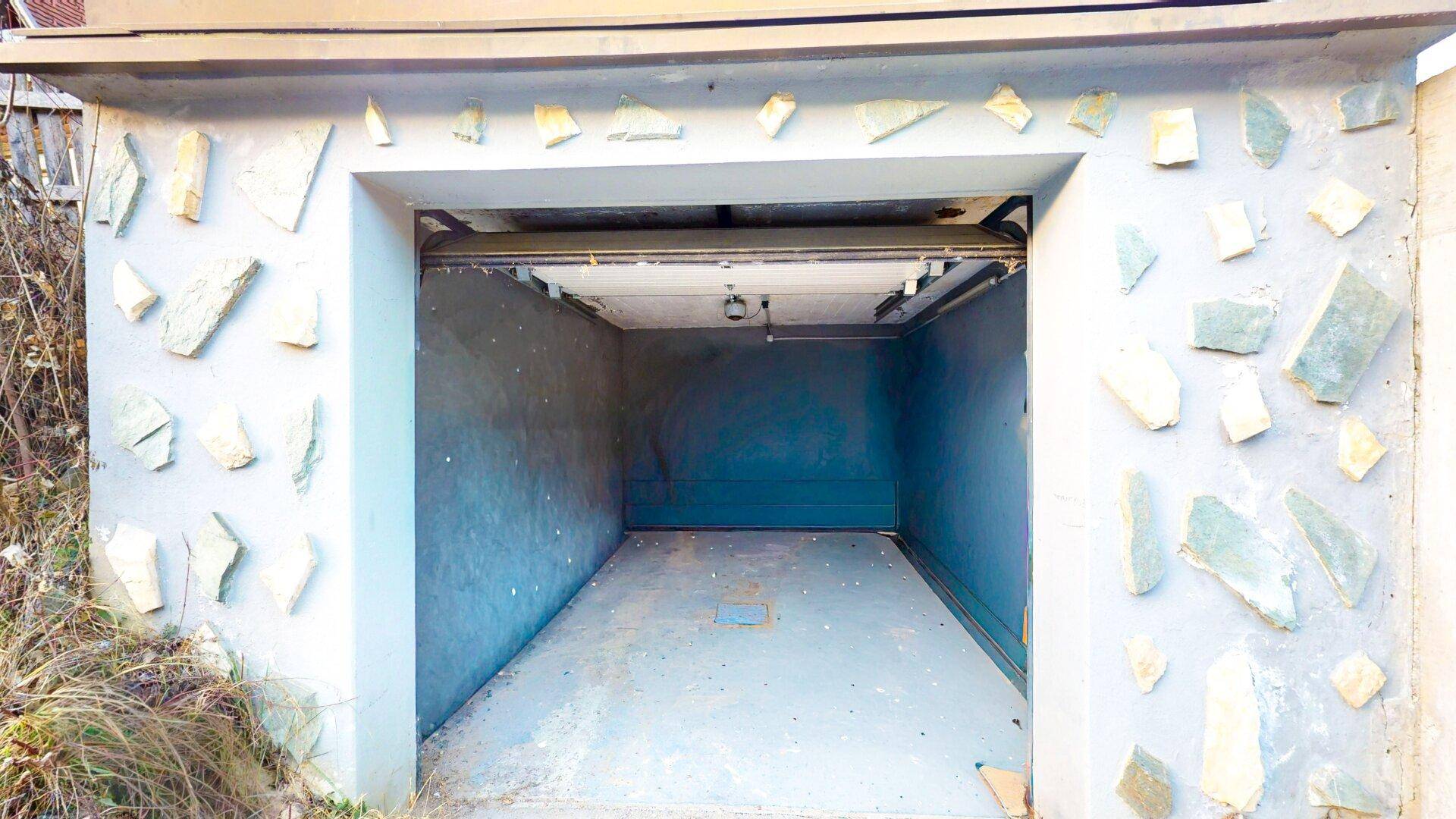 Eingang zu einer Garage mit dekorativer Steinverkleidung und Rolltor.