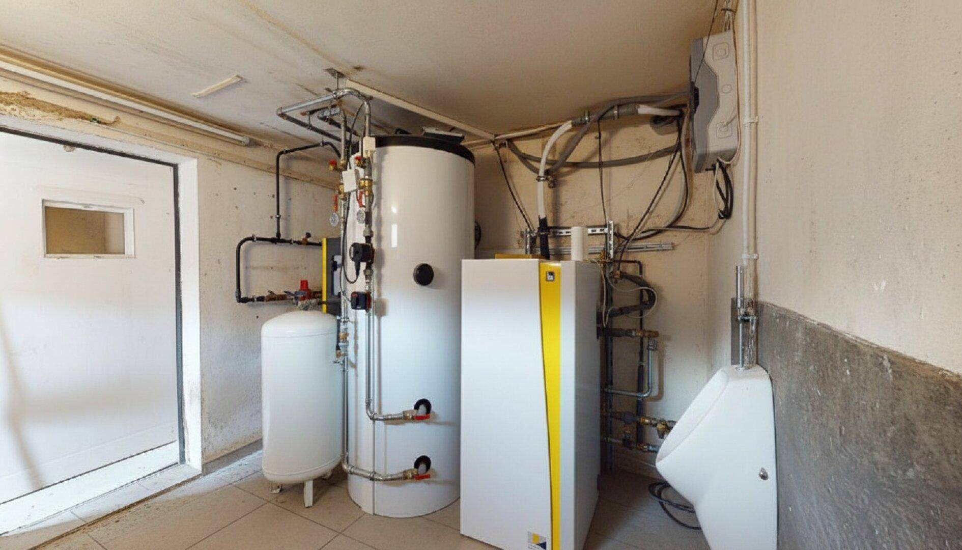 Technikraum mit moderner Heizungsanlage und Warmwasserspeichern, inklusive Urinal.