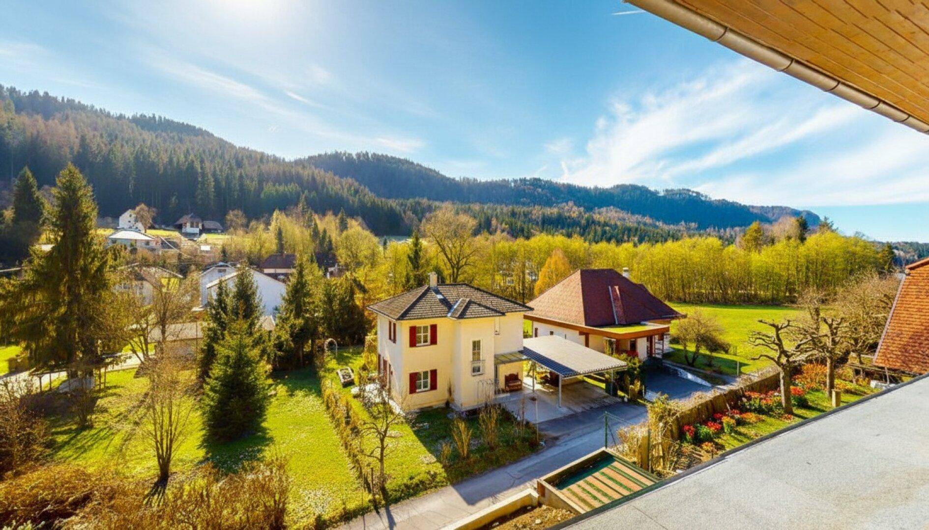 Balkon mit Panoramablick auf die grüne Umgebung und die charmanten Nachbarhäuser.