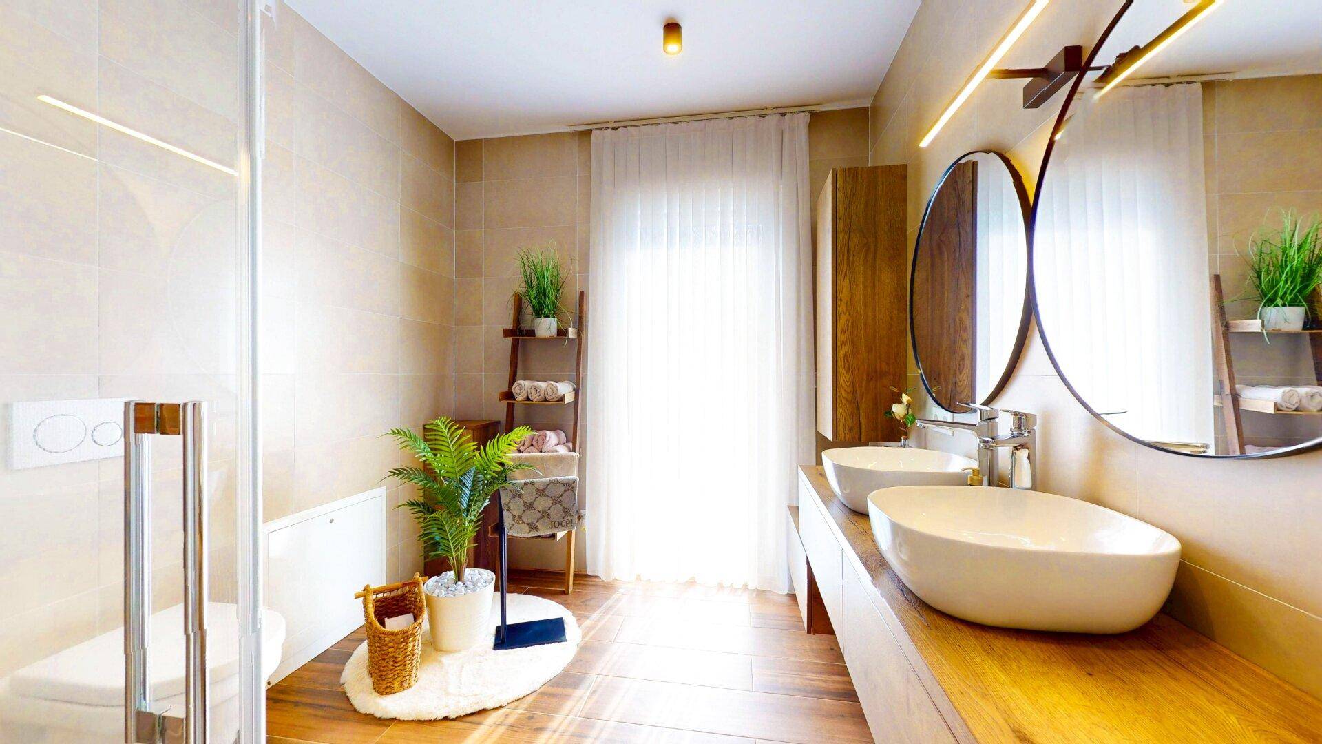 Modernes Badezimmer mit Doppelwaschbecken, großer Dusche und hellen Fliesen.