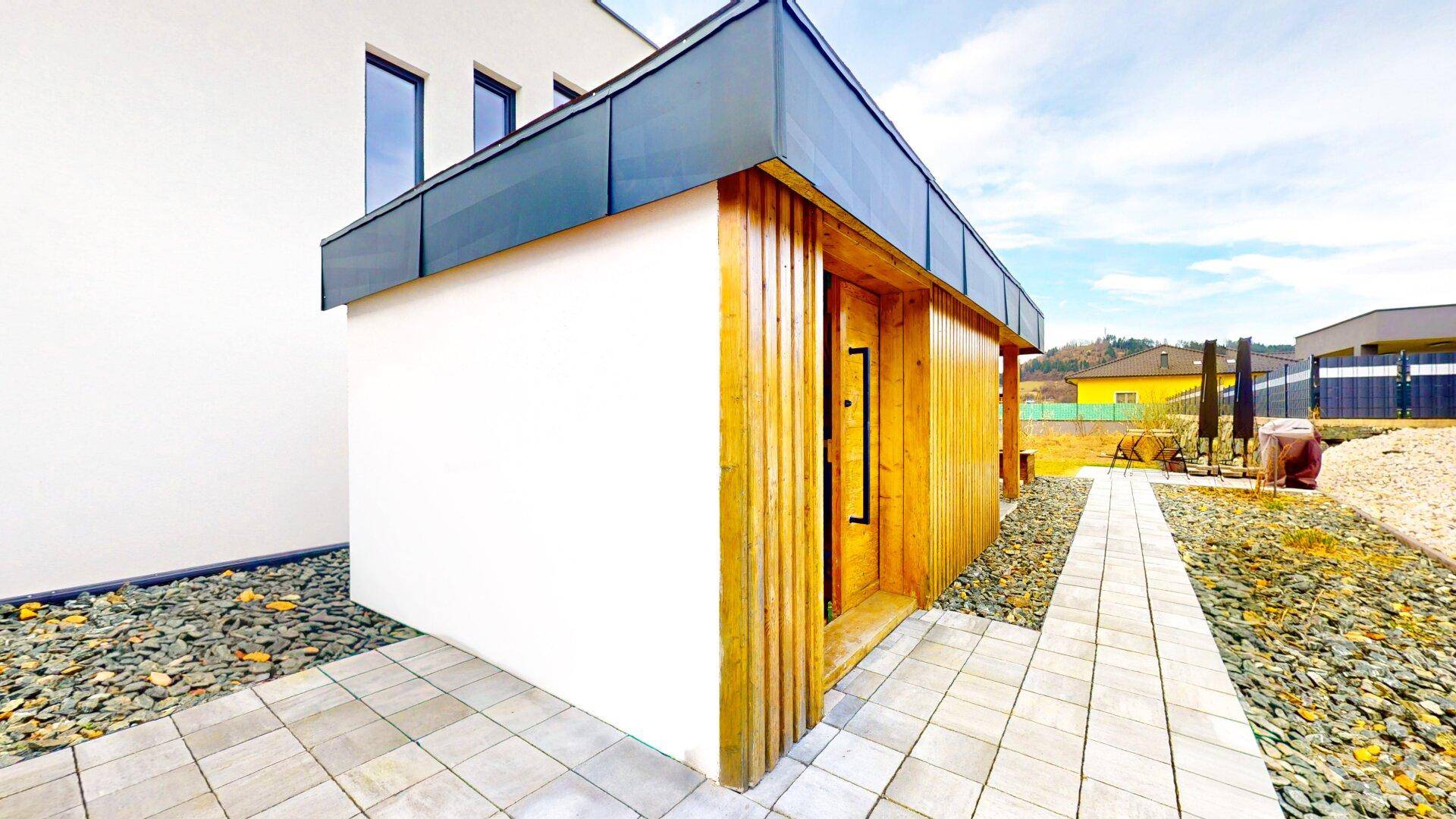 Moderner Eingangsbereich des Hauses mit Holzverkleidung und gepflastertem Weg.