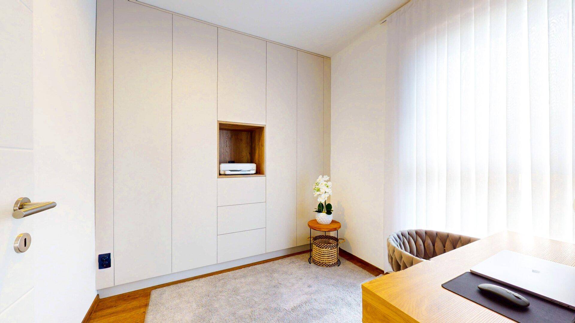 Modernes Arbeitszimmer mit Einbauschränken und hellem Schreibtisch.