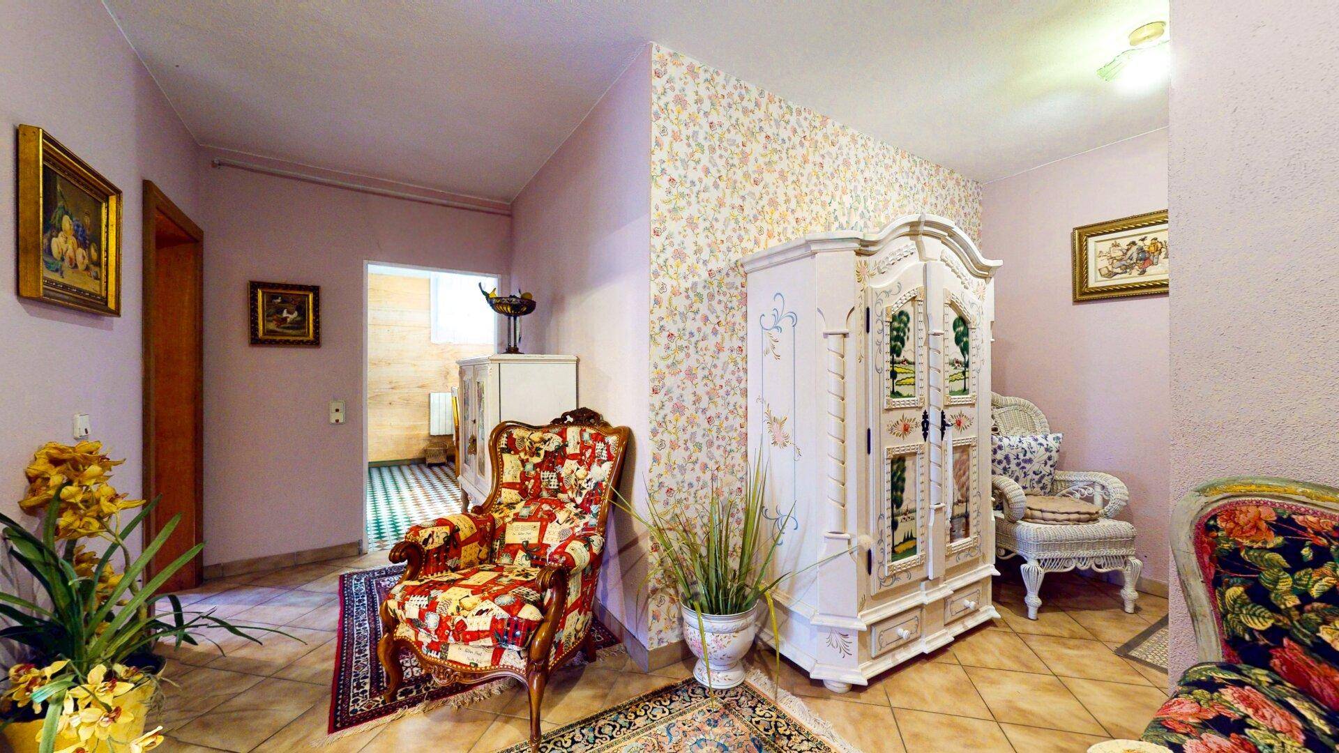 Heller Flur mit floraler Tapete, dekorativem Schrank und traditionellen Möbeln.