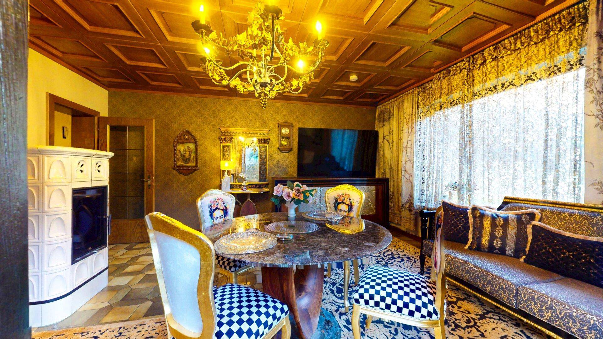 Traditioneller Essbereich mit Kachelofen, Holzkassettendecke und opulenten Möbeln.