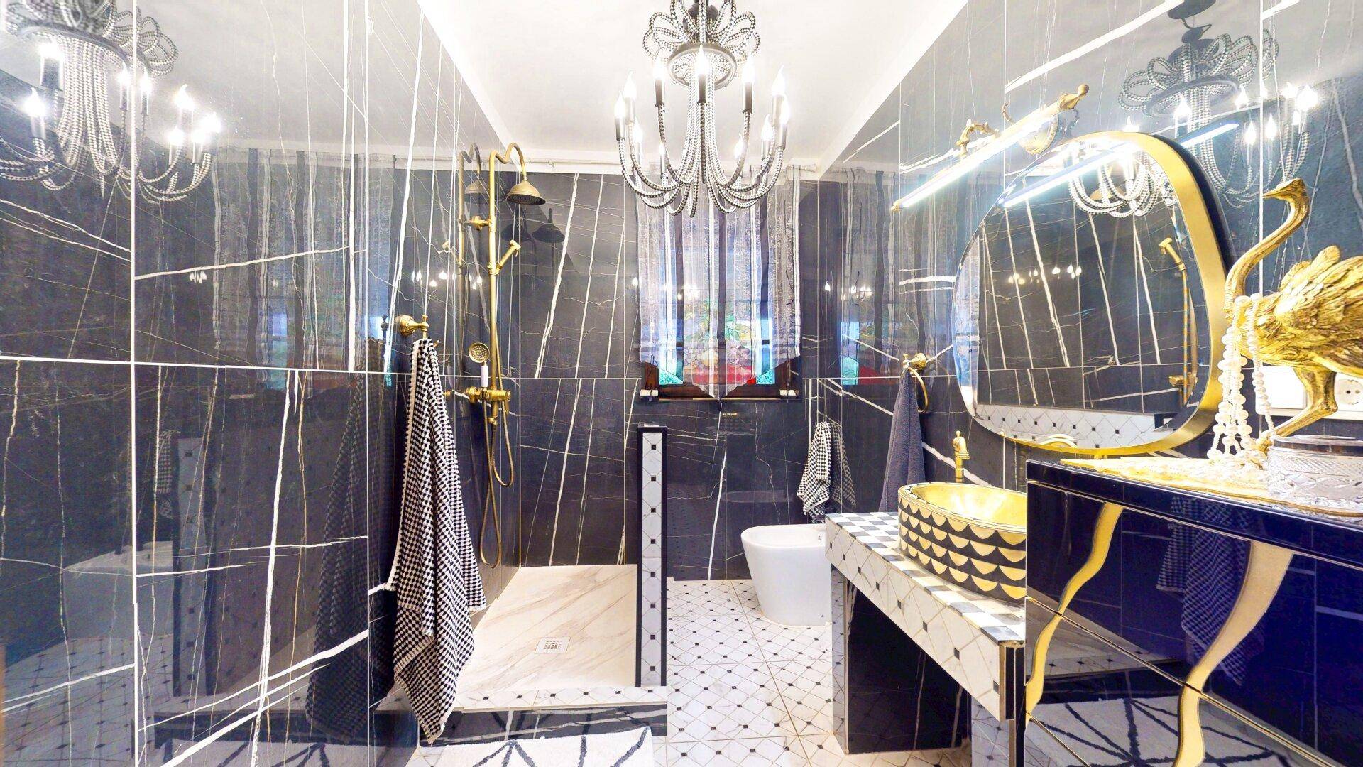 Luxuriöses Badezimmer mit dunklen Marmorfliesen, goldfarbenen Armaturen und moderner Dusche.