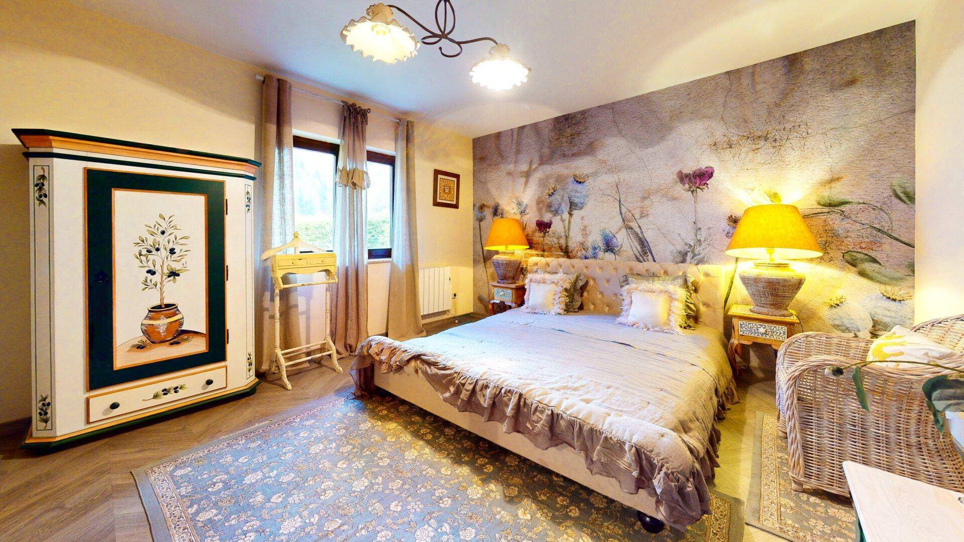 Ruhiges Schlafzimmer mit großem Bett, floraler Wandgestaltung und Holzboden.