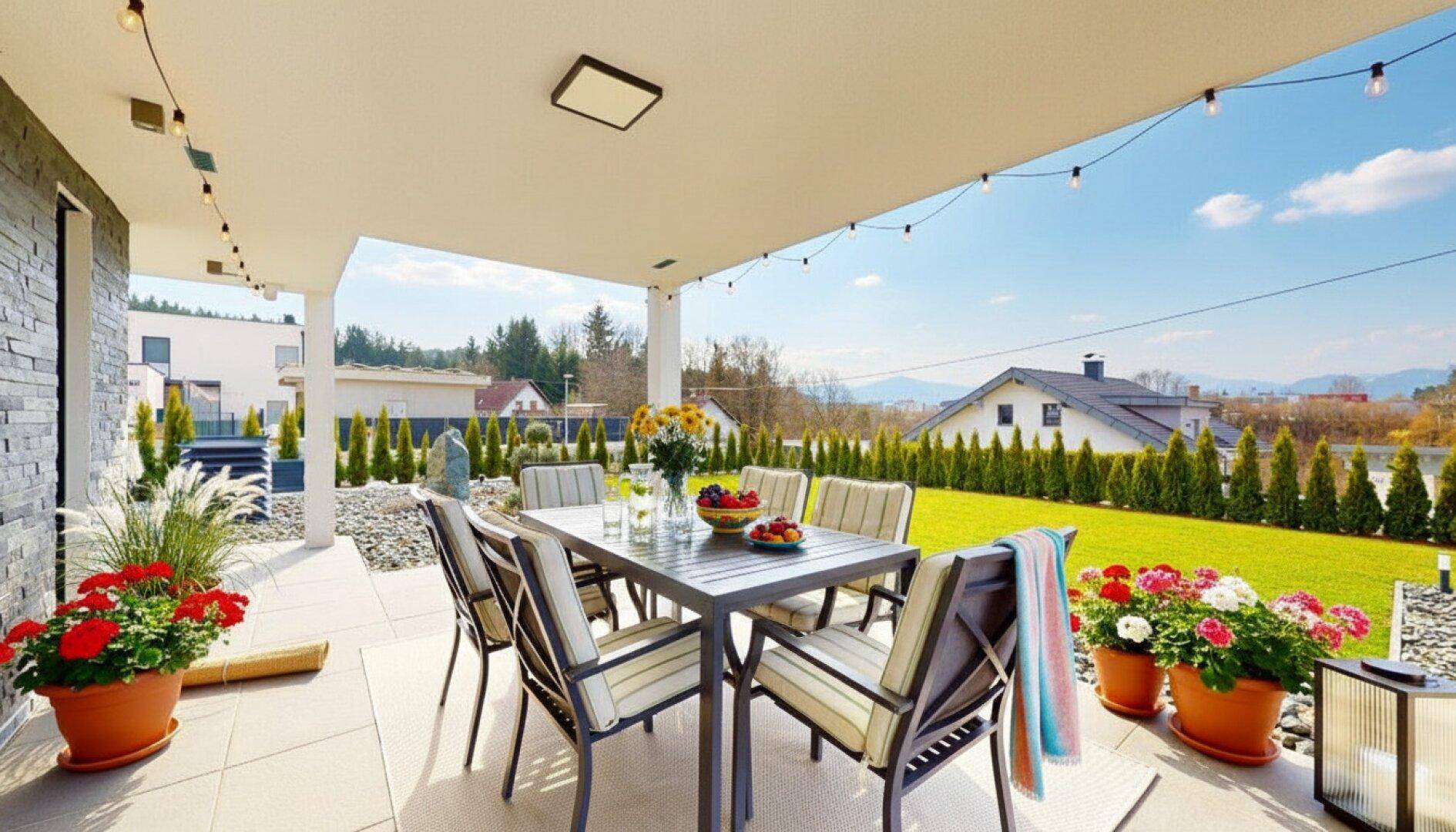 Große überdachte Terrasse mit Esstisch und Blick auf den gepflegten Garten.
