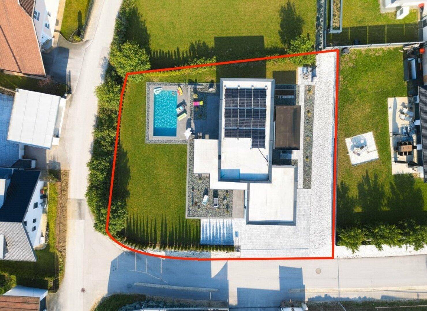 Luftaufnahme des Grundstücks mit Pool, Garten und Photovoltaikanlage auf dem Dach.