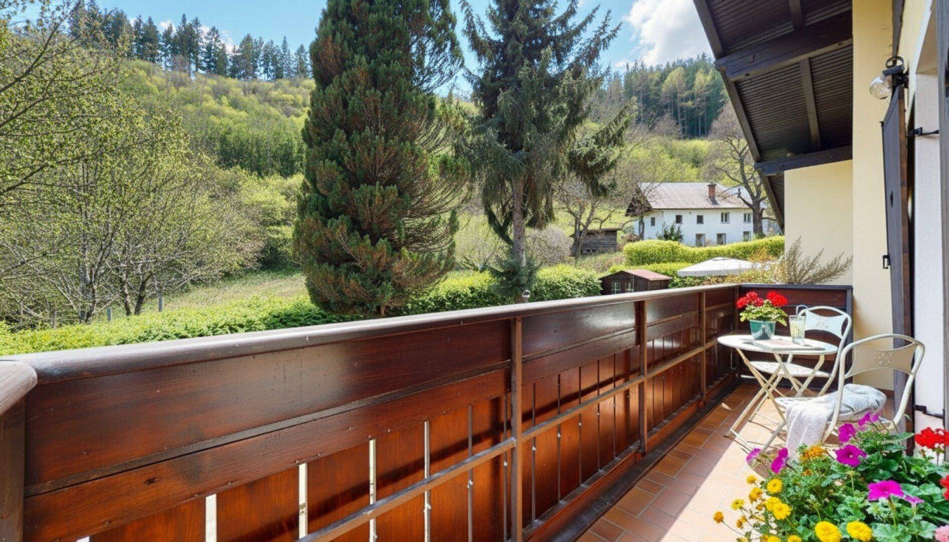 Geräumiger Balkon mit Holzboden und weitem Blick auf die grüne Hügellandschaft.