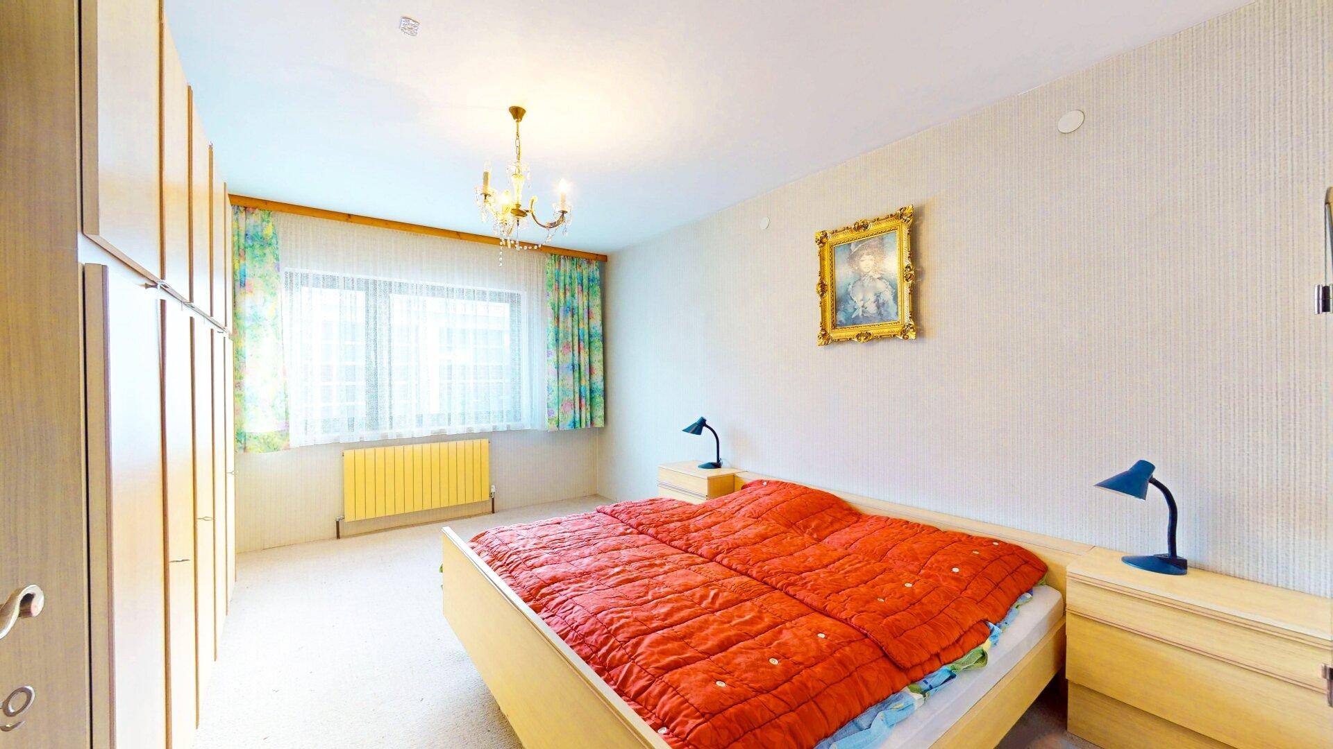 Geräumiges Schlafzimmer mit Bett, Nachttischen und praktischen Einbauschränken entlang der Wand.