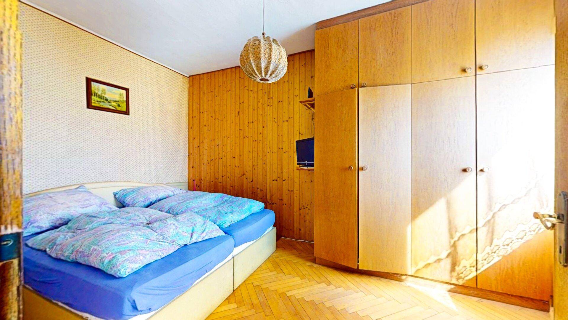 Schlafzimmer mit Holzvertäfelung, zwei Einzelbetten und einem großen Kleiderschrank.