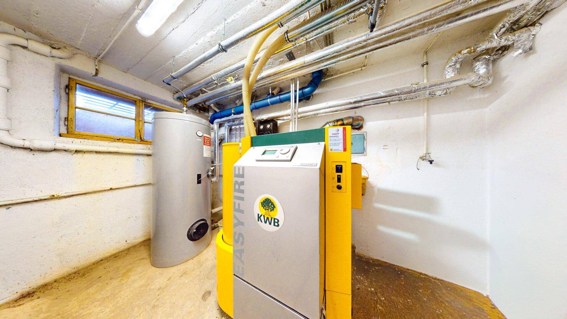 Heizungsraum im Keller mit moderner KWB Easyfire Heizungsanlage und Warmwasserspeicher.