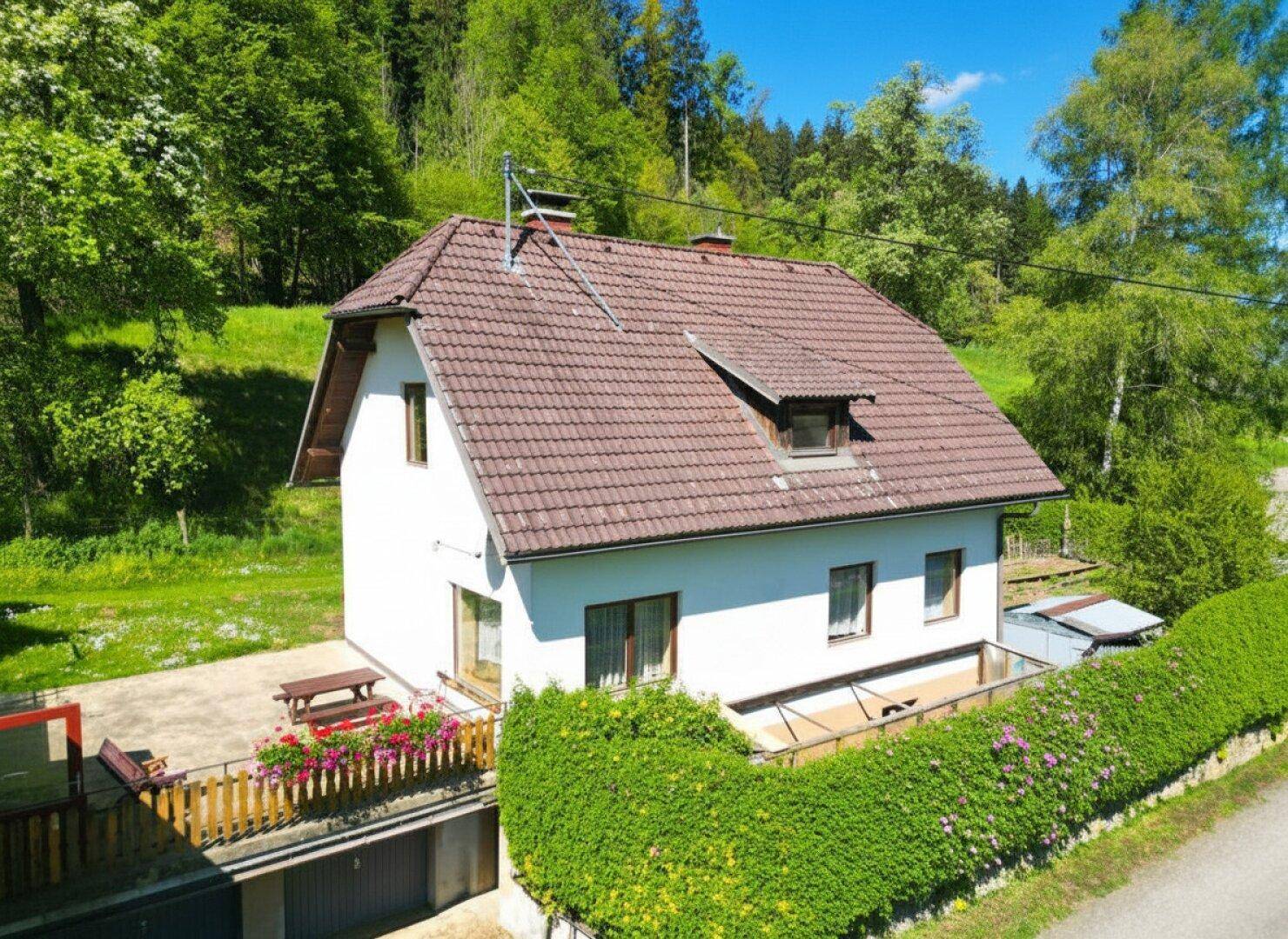 Freistehendes Haus mit Satteldach, umgeben von viel Grün und einem gepflegten Gartenbereich.