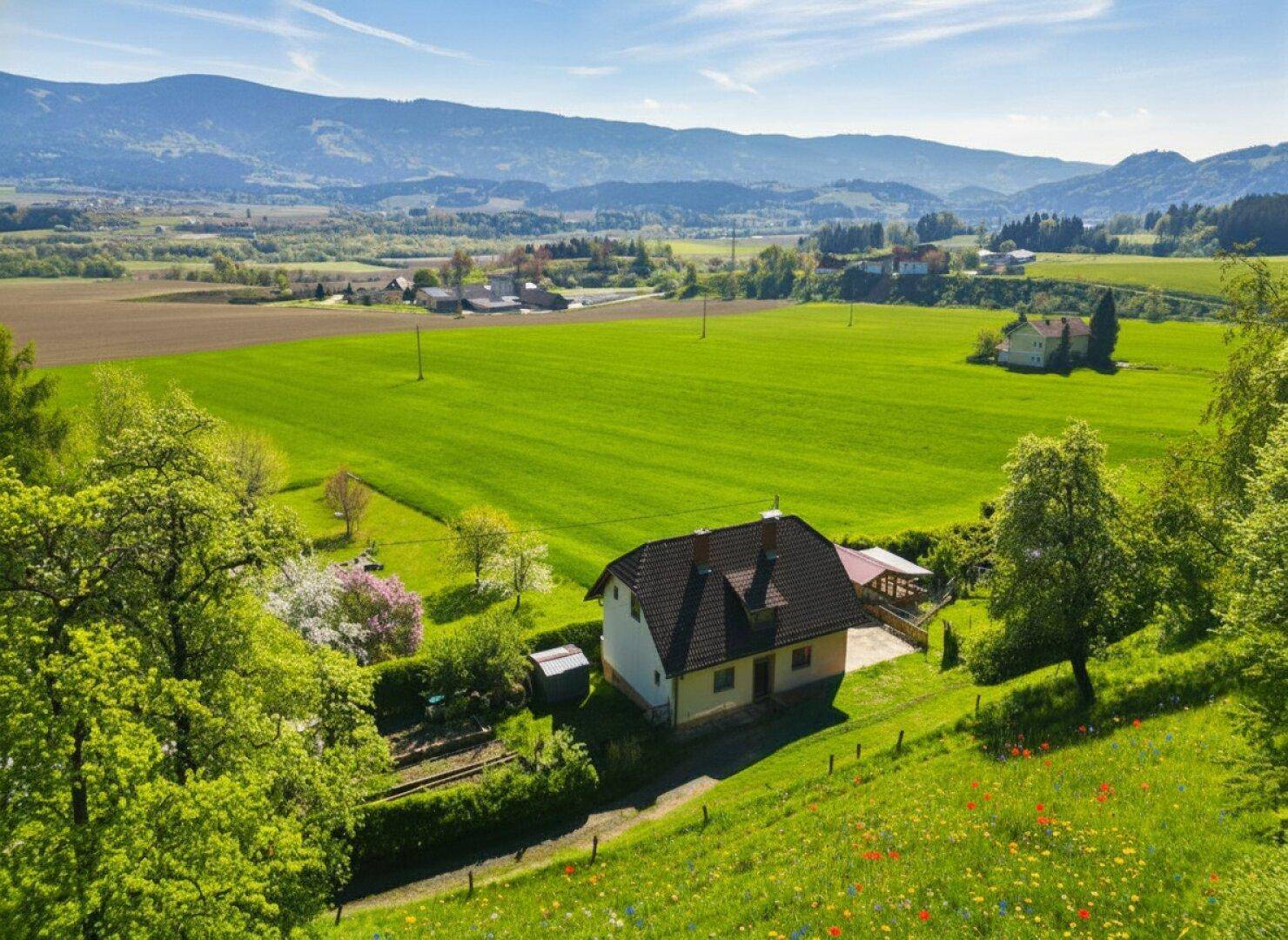 Luftaufnahme des Hauses in ländlicher Umgebung, umgeben von Feldern und Wäldern mit Bergsicht.