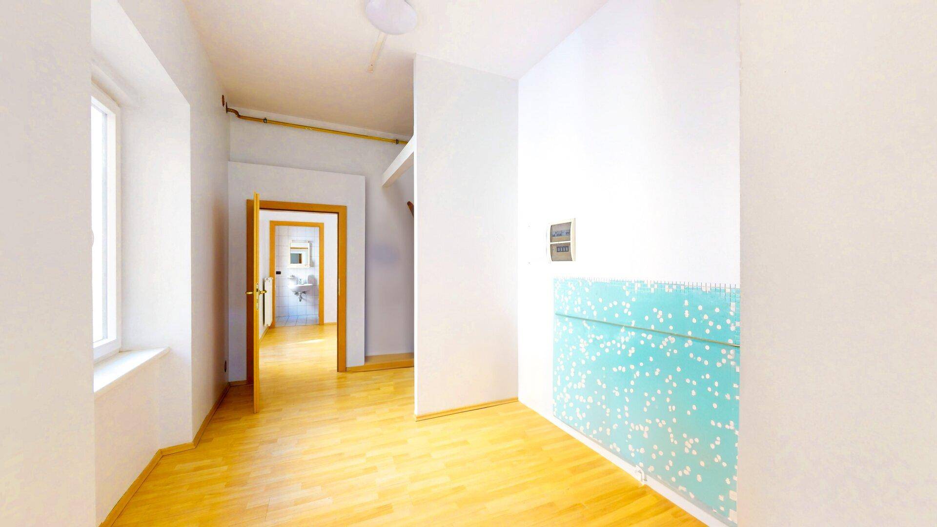Heller Raum mit Holzboden, weißen Wänden und einem dekorativen Element an der Wand.