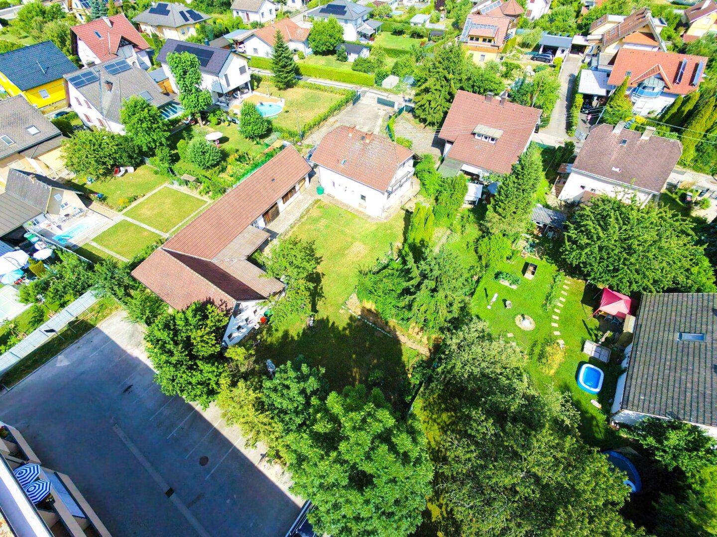 Luftaufnahme des Anwesens mit großem Garten und umliegenden Wohnhäusern in grüner Umgebung.