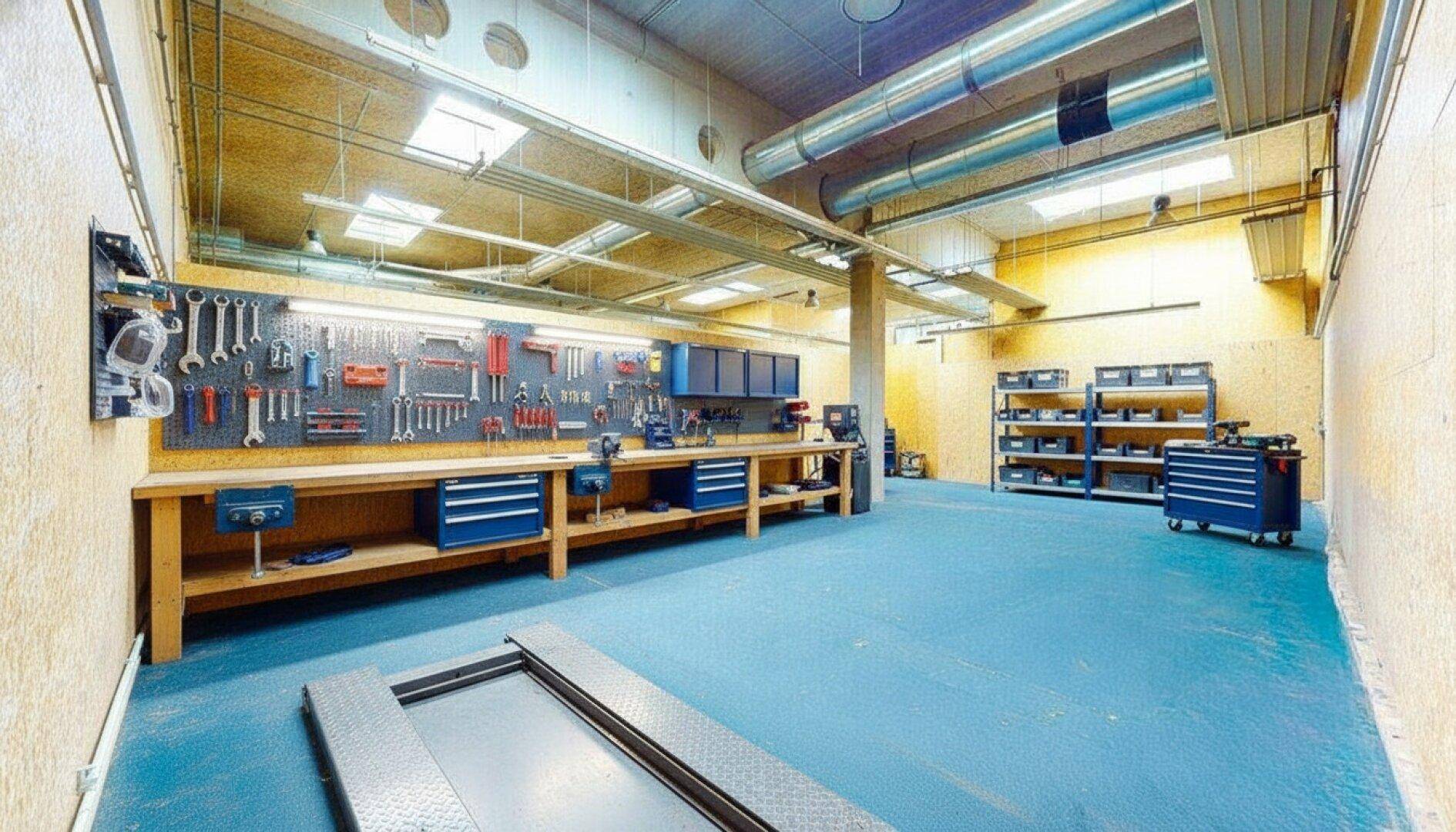 Gut ausgestattete Werkstatt mit Werkbänken, Werkzeugwand und Hebebühne, ideal für handwerkliche Arbeiten.