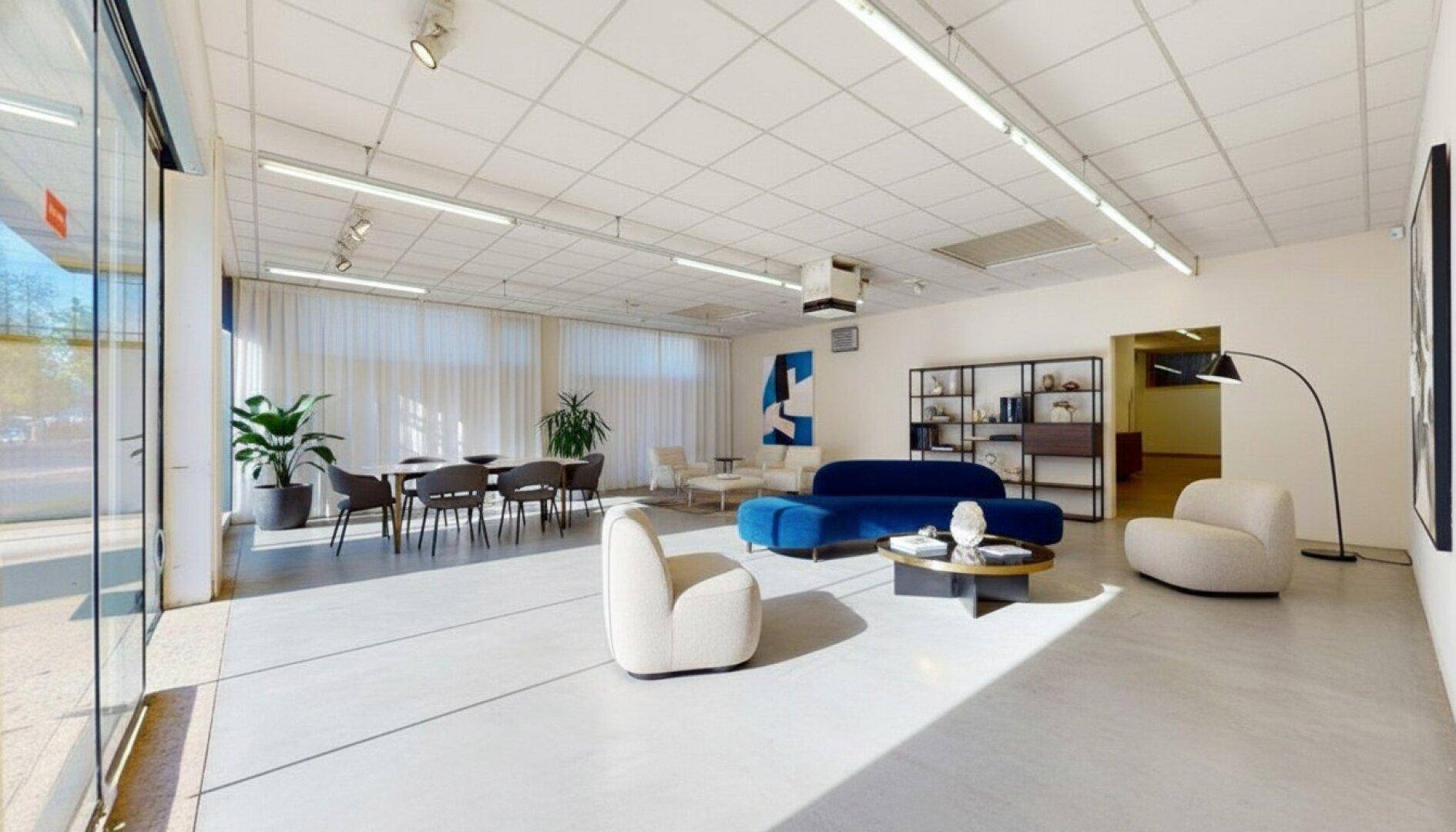 Moderner Loungebereich mit stilvollen Möbeln, großen Fenstern und viel natürlichem Licht, ideal für Empfänge oder Pausen.