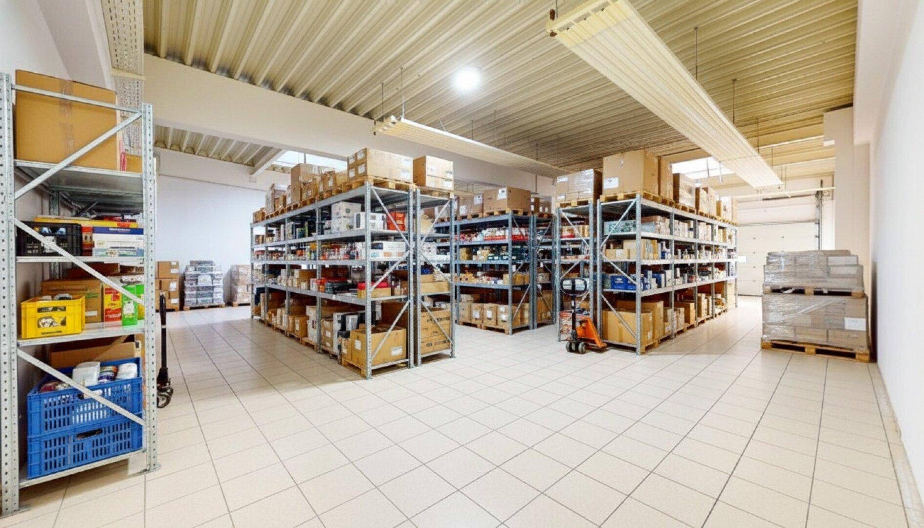 Weitläufiger Lagerraum mit Metallregalen, gefüllt mit verschiedenen Produkten und Fliesenboden.