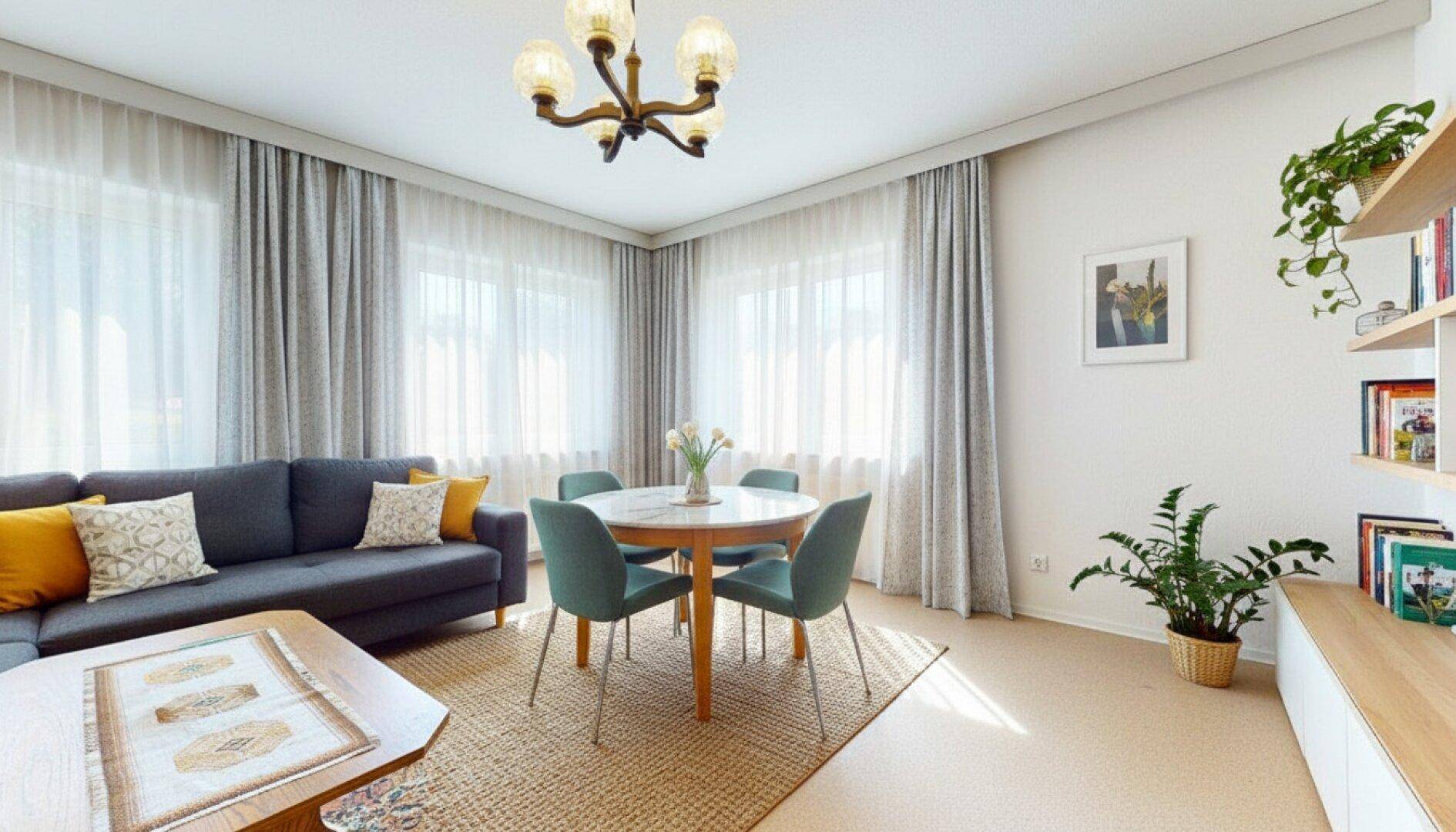 Gemütlicher Wohn-Essbereich mit Sofa, Esstisch und großen Fenstern für viel Tageslicht.