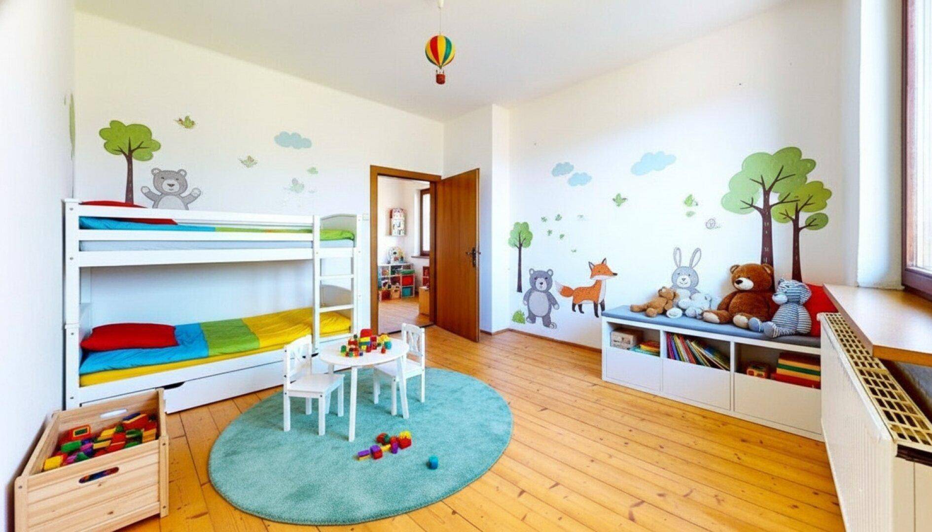 Freundliches Kinderzimmer mit Etagenbett, Spielbereich und farbenfrohen Wanddekorationen.