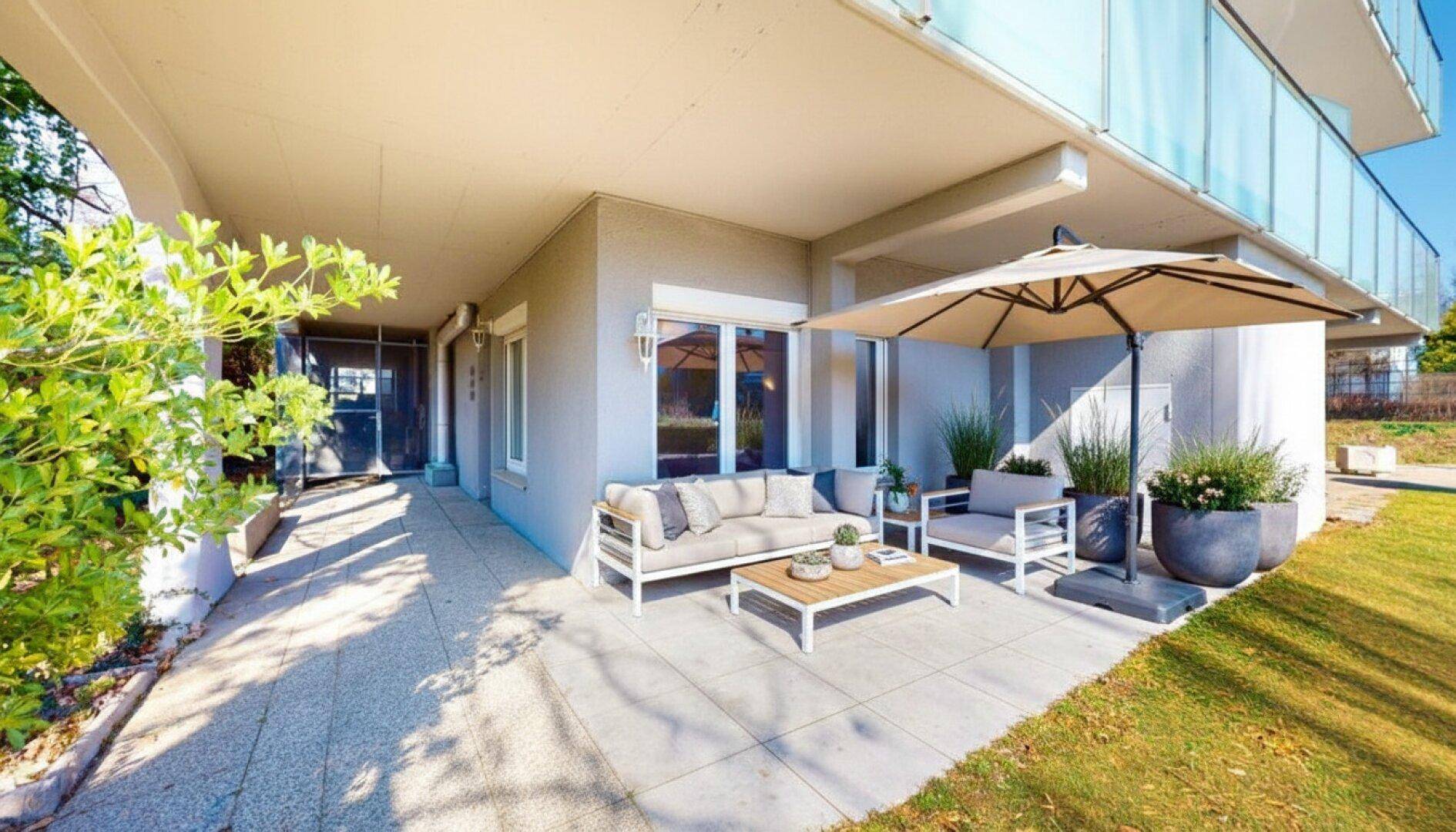 Geräumige Terrasse mit modernen Gartenmöbeln und Sonnenschirm, ideal für entspannte Stunden im Freien.