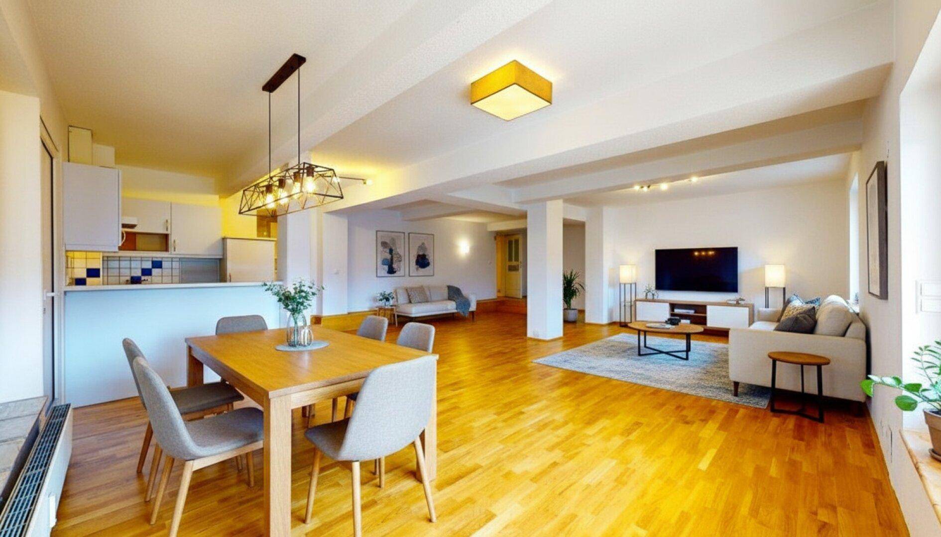 Heller, offener Wohn- und Essbereich mit Holzboden und moderner Einrichtung, ideal für geselliges Beisammensein.
