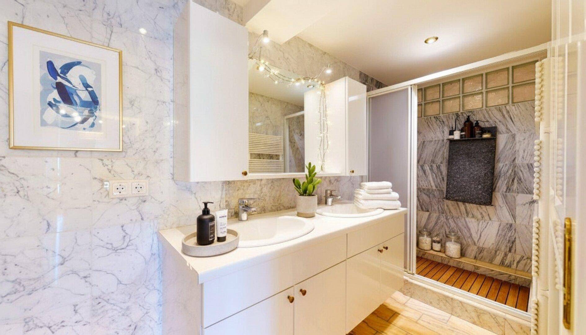 Modernes Badezimmer mit Doppelwaschbecken, Marmorfliesen und begehbarer Dusche.