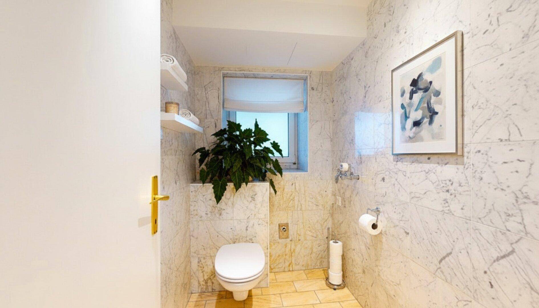 Helles WC mit Marmorfliesen, Fenster und moderner Toilette.