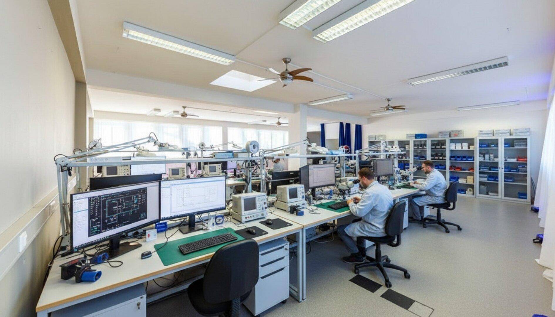 Modernes Labor mit mehreren Arbeitsplätzen, Computern und elektronischer Ausrüstung für technische Arbeiten.