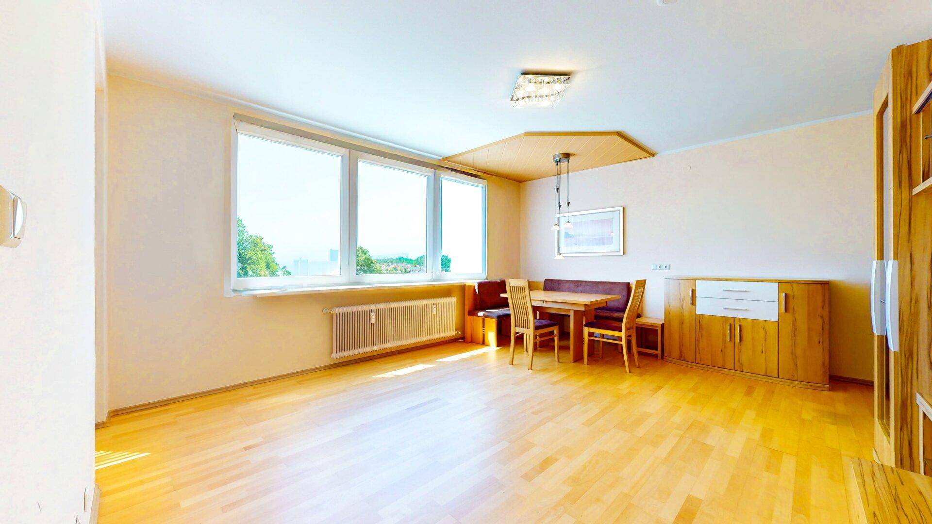 Geräumiges Wohn- und Esszimmer mit Holzboden und großem Fenster, bereit zur individuellen Gestaltung.