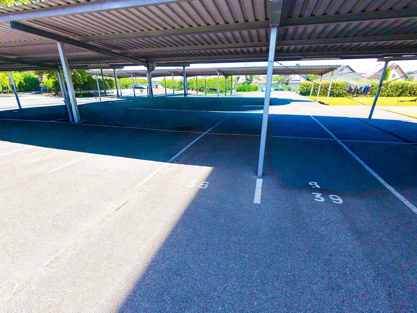 Überdachte Parkplätze mit nummerierten Stellflächen, bieten Schutz für Fahrzeuge vor Witterungseinflüssen.