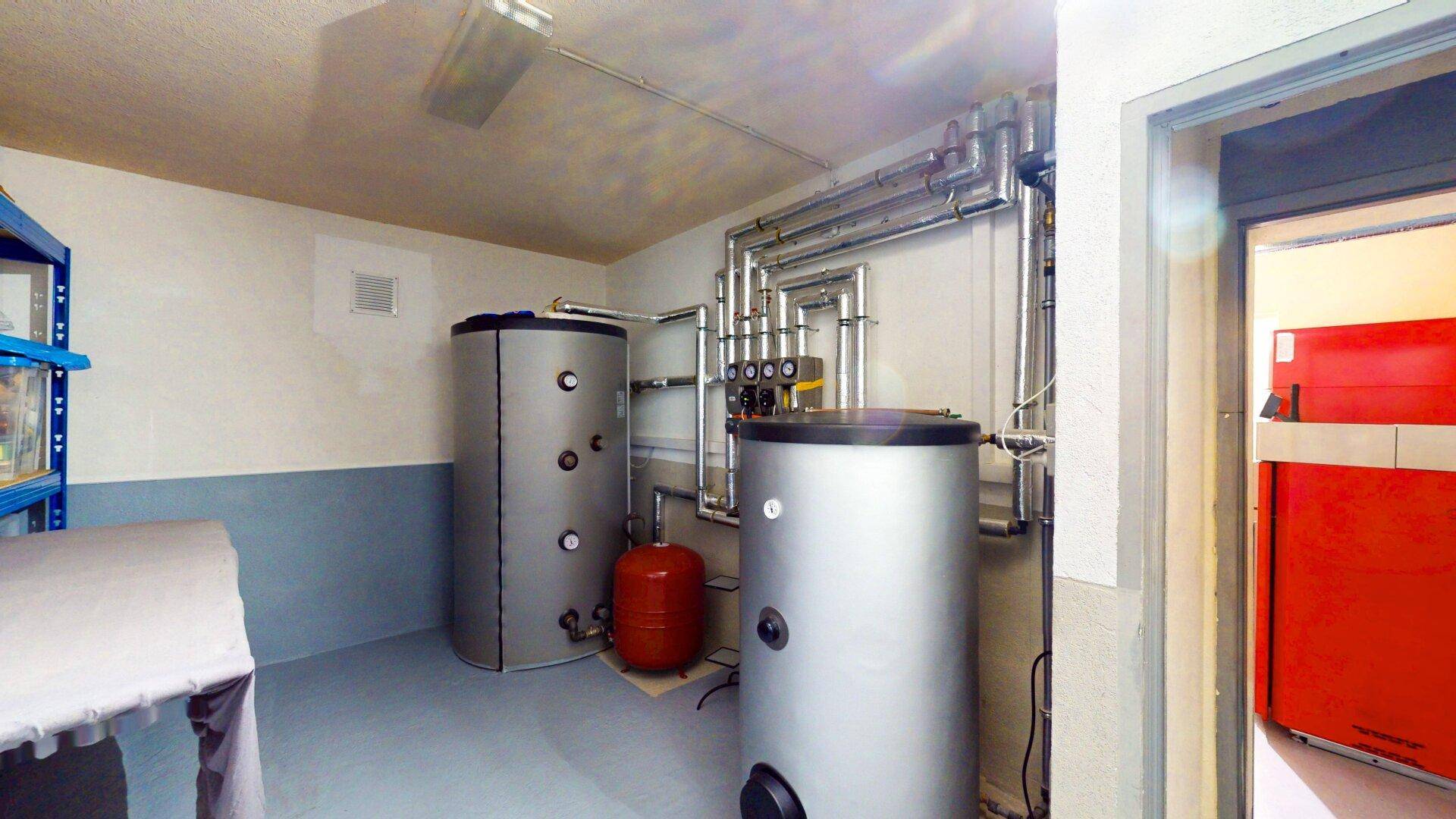 Heizungsraum mit Warmwasserspeichern und komplexer Rohrinstallation für die Haustechnik.