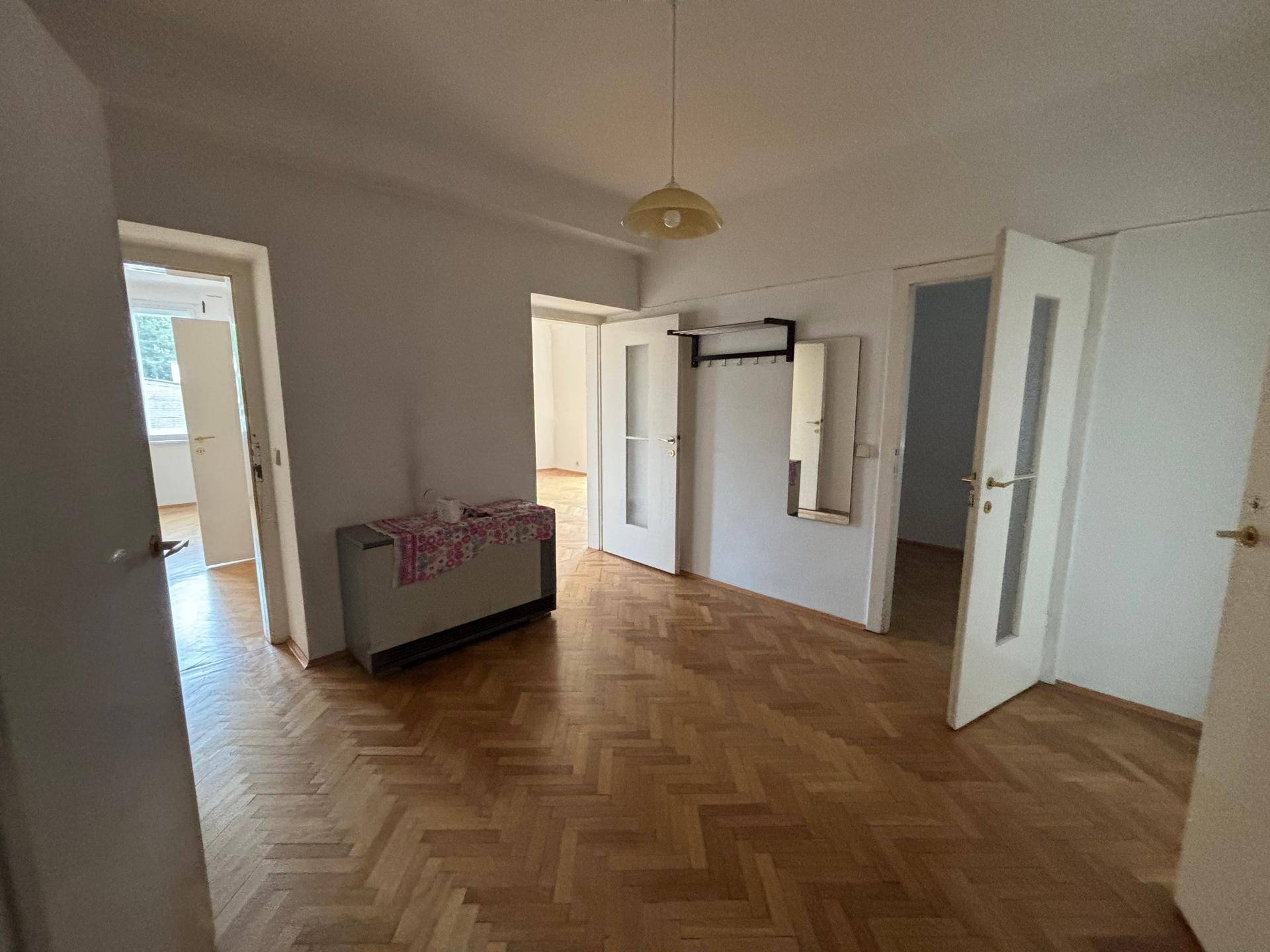 Geräumiger Flur mit Fischgrätparkett, Garderobe und Zugang zu verschiedenen Zimmern der Wohnung.