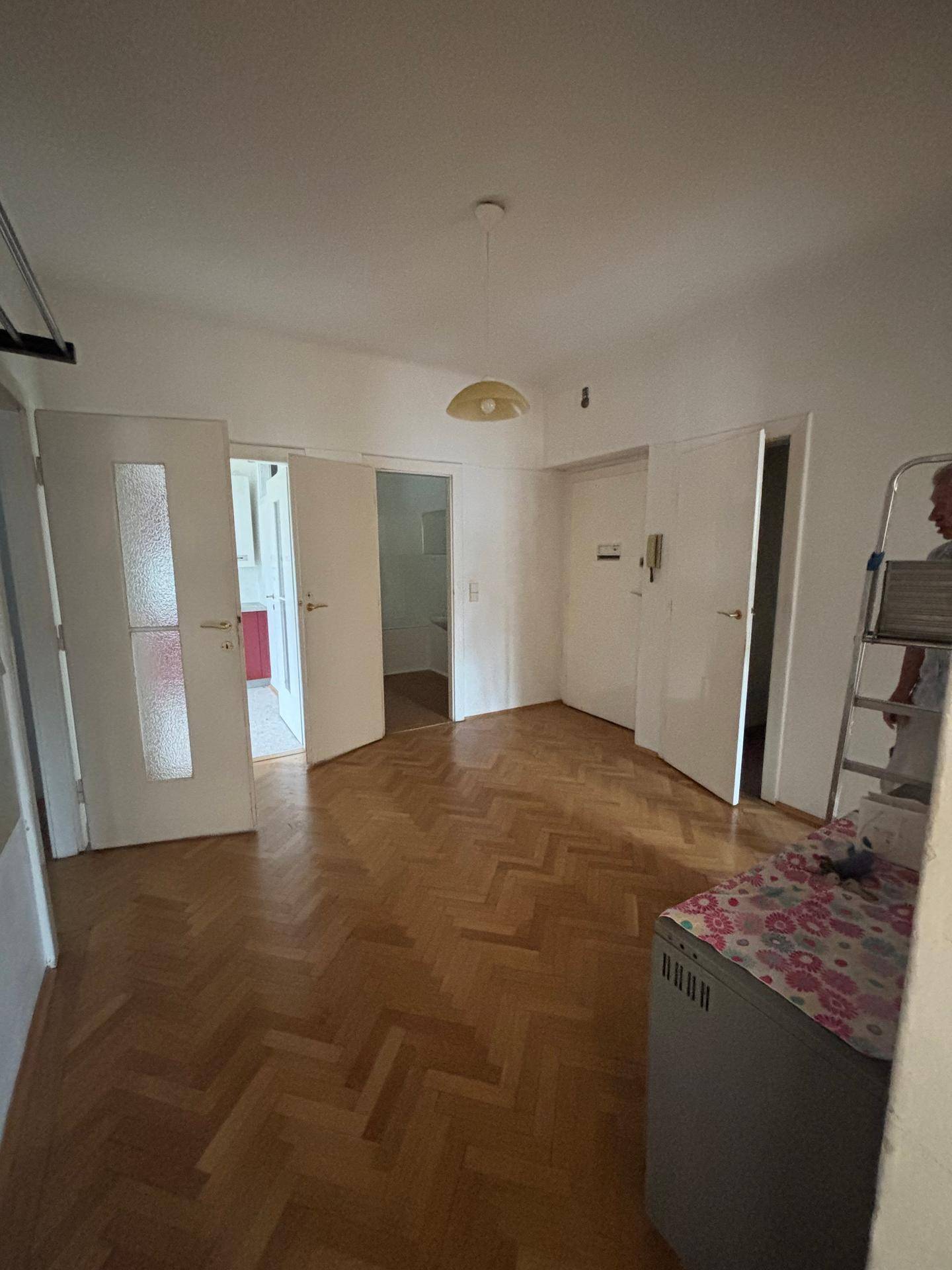 Flur mit Fischgrätparkett und mehreren Türen, der die verschiedenen Bereiche der Wohnung verbindet.