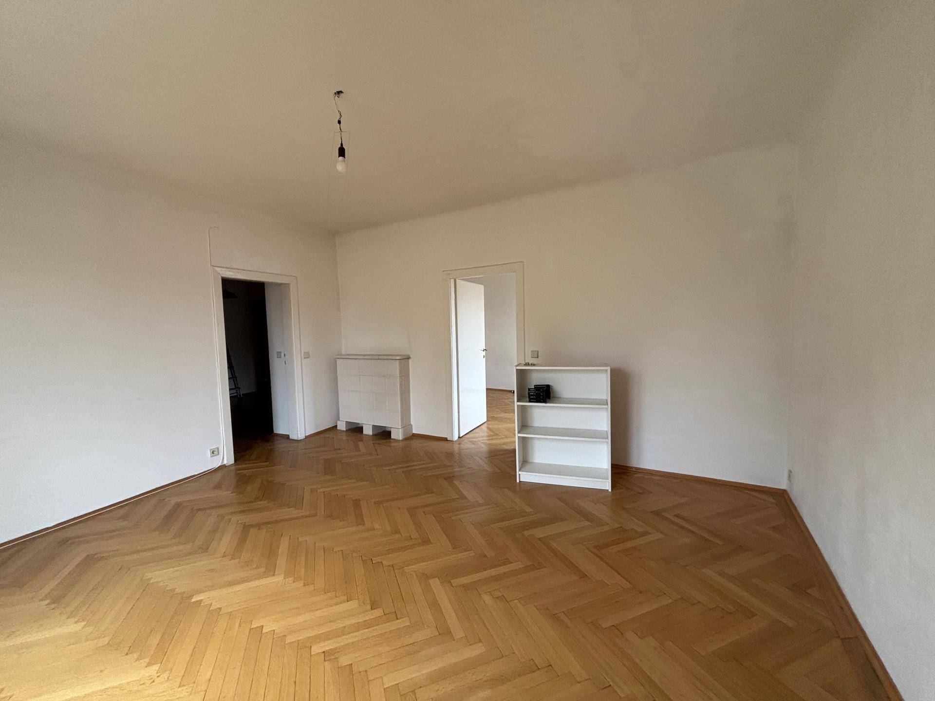 Geräumiges Zimmer mit Fischgrätparkett und weißen Wänden, bereit zur individuellen Gestaltung.