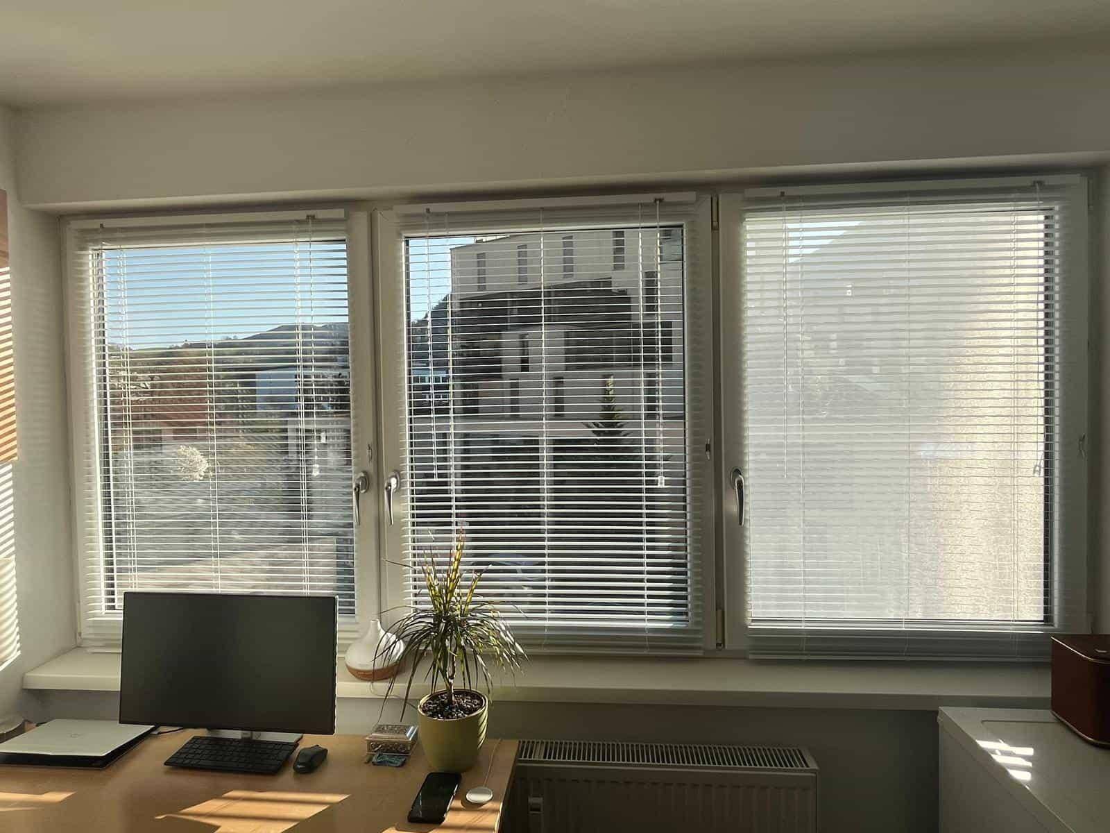 Heller Raum mit großen Fenstern und Jalousien, ideal als Arbeitszimmer oder Büro nutzbar.