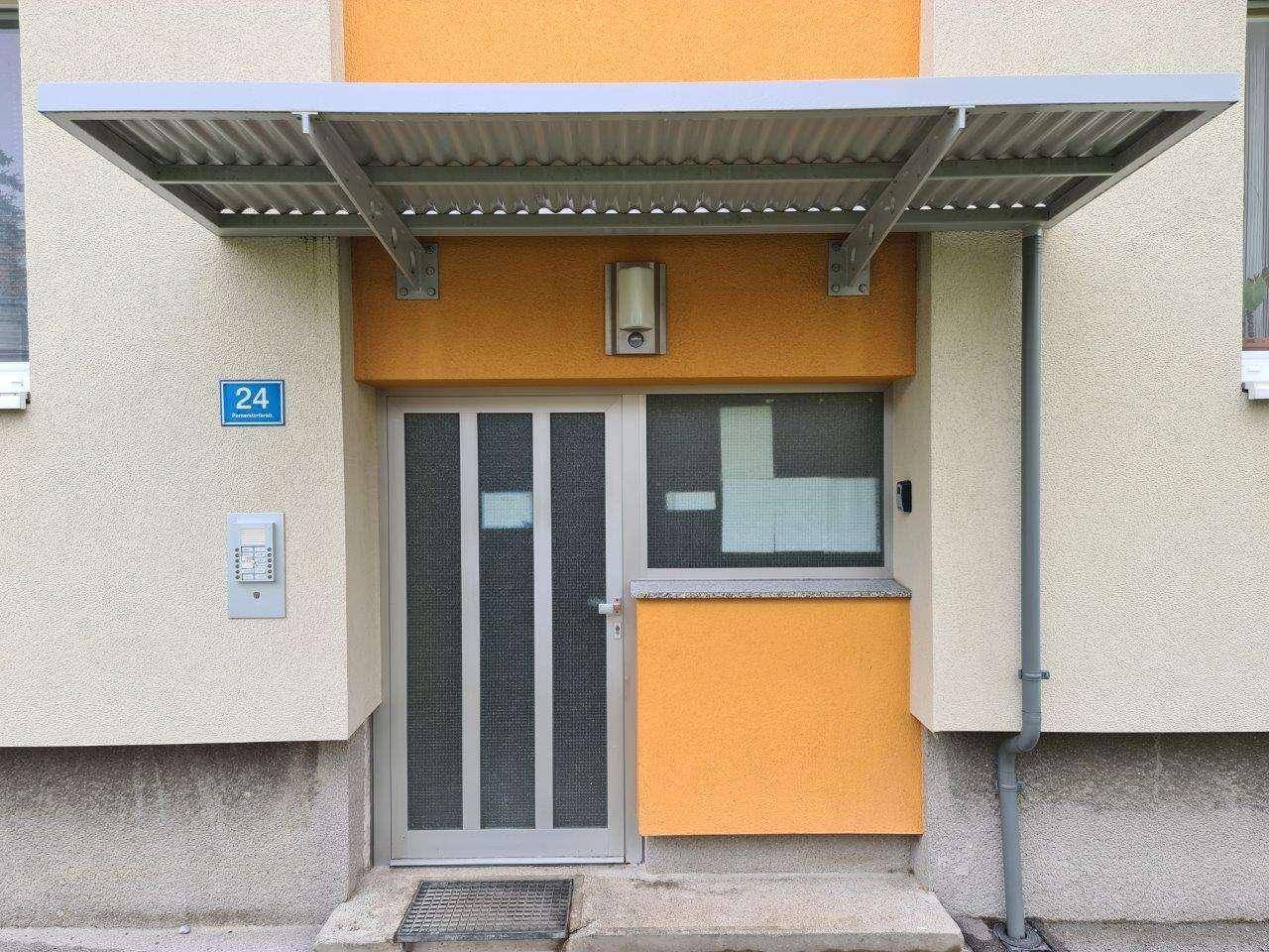 Eingangsbereich eines Mehrfamilienhauses mit Vordach und Hausnummer 24.