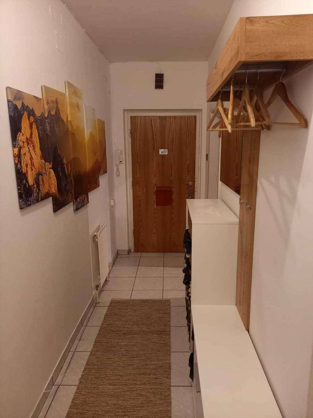 Eingerichteter Flur mit Fliesenboden, Garderobe und Wandbildern, die eine gemütliche Atmosphäre schaffen.