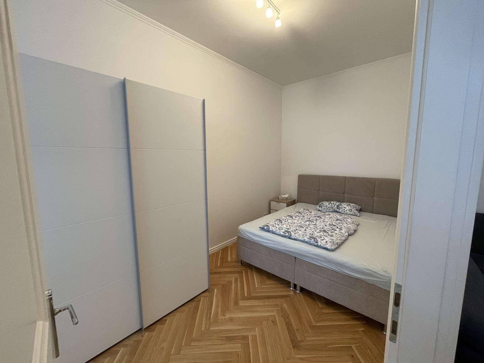Gemütliches Schlafzimmer mit Doppelbett, großem Kleiderschrank und Fischgrätparkettboden.