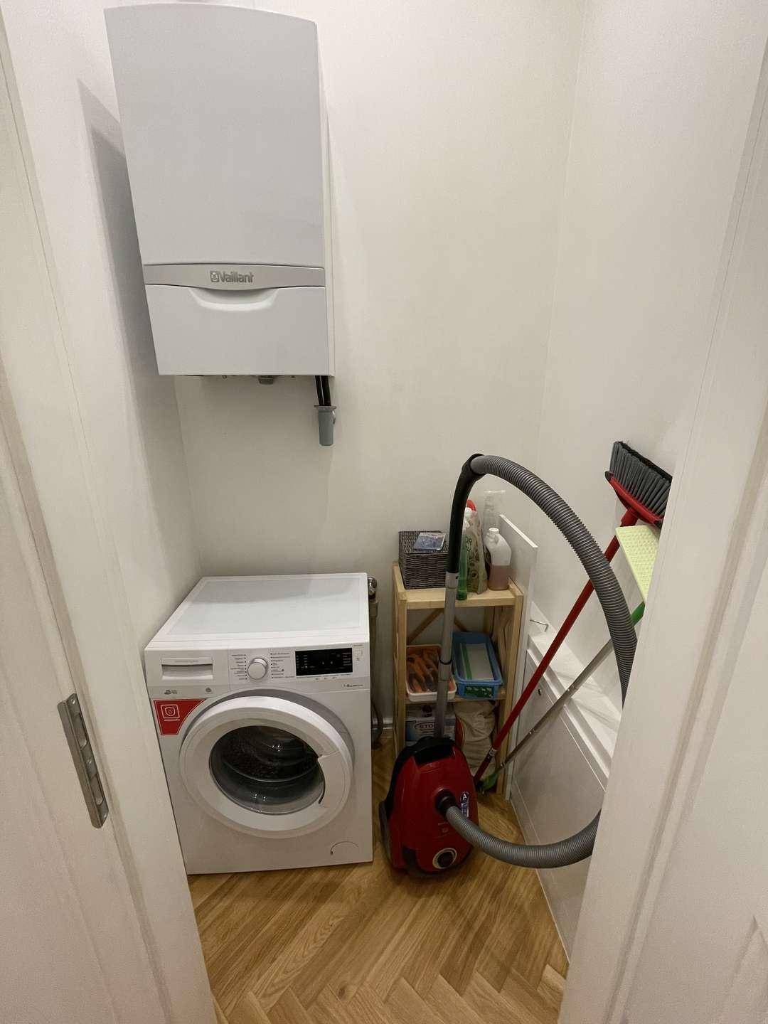 Praktischer Hauswirtschaftsraum mit Waschmaschine, Heizkessel und Stauraum für Reinigungsgeräte.