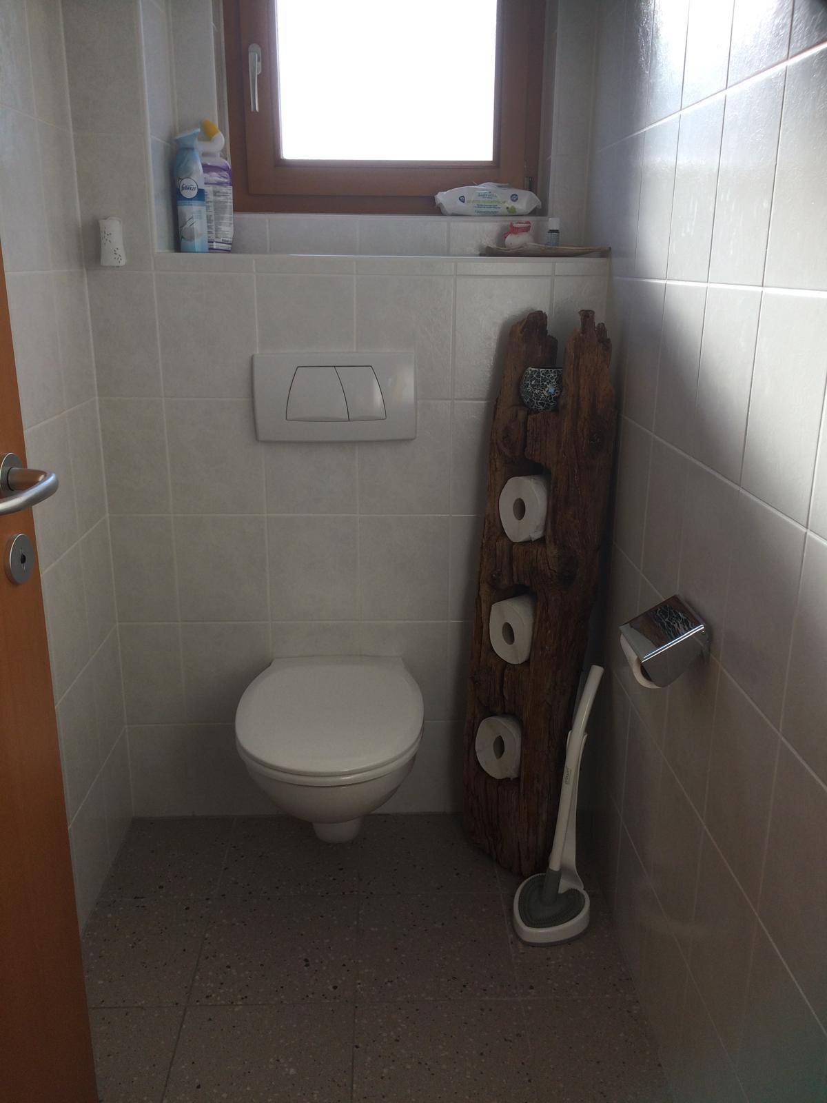 Separates WC mit wandhängender Toilette, weißen Fliesen und einem Fenster für Belüftung.