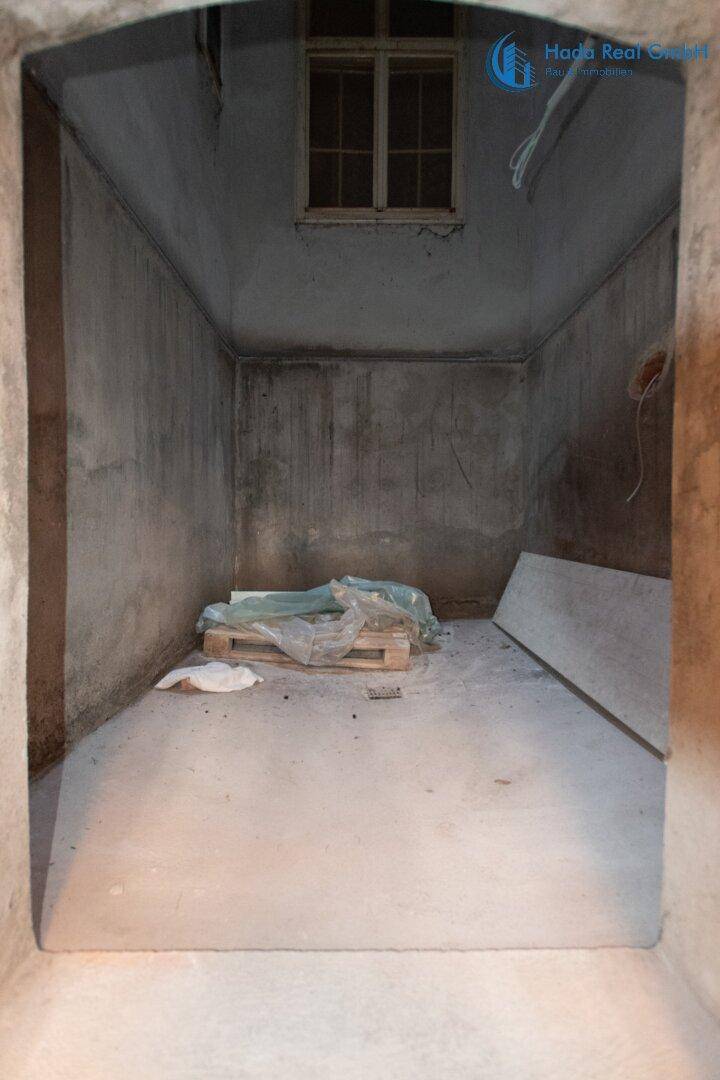 Unfertiger Kellerraum mit Betonwänden und einem kleinen Fenster, ideal als Lagerfläche.