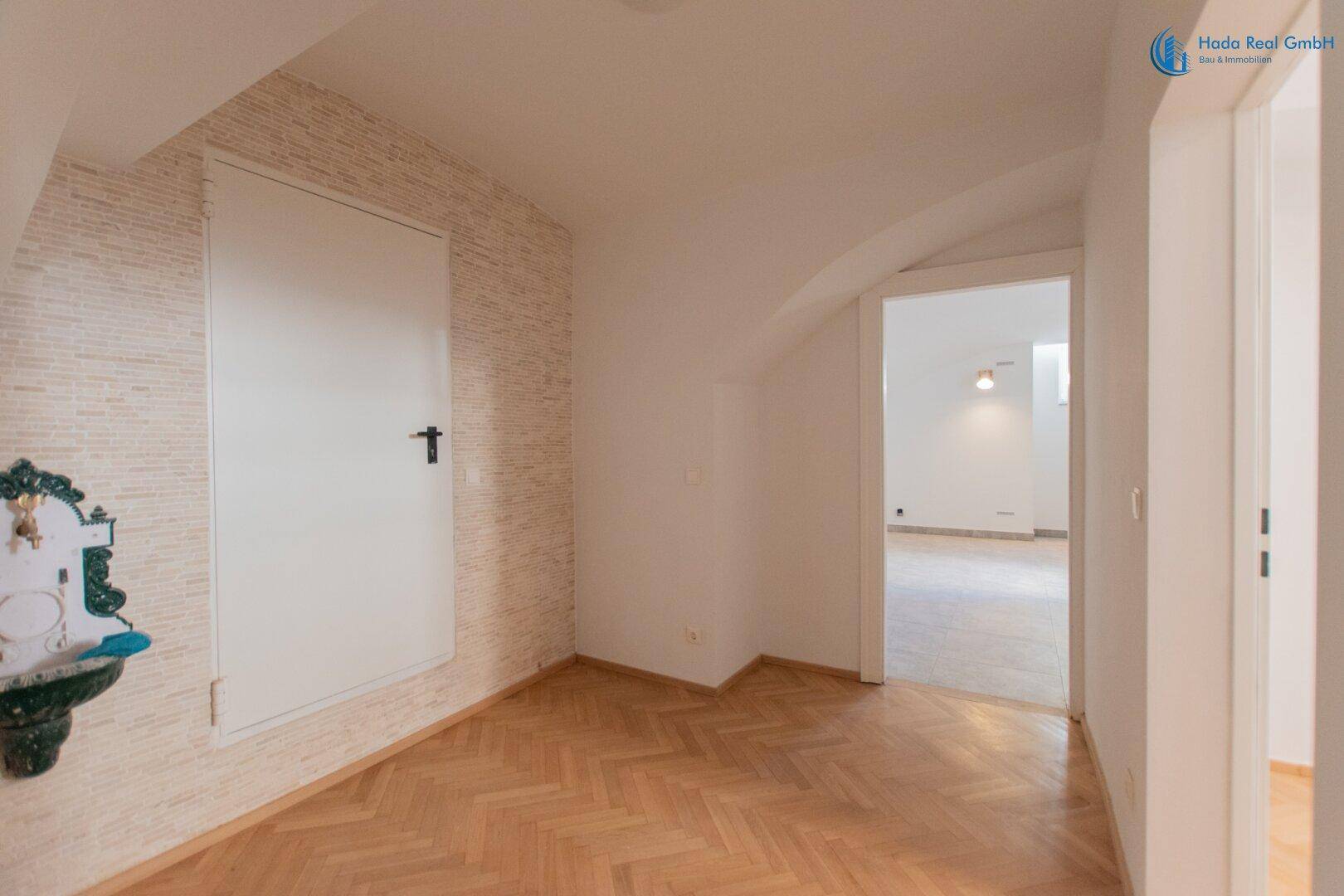 Kleiner Raum mit Fischgrätparkett und dekorativer Wand, ausgestattet mit einem kleinen Waschbecken.
