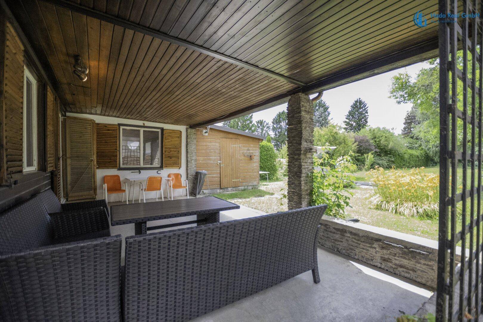 Gemütliche überdachte Terrasse mit Rattanmöbeln und weitem Blick ins Grüne.