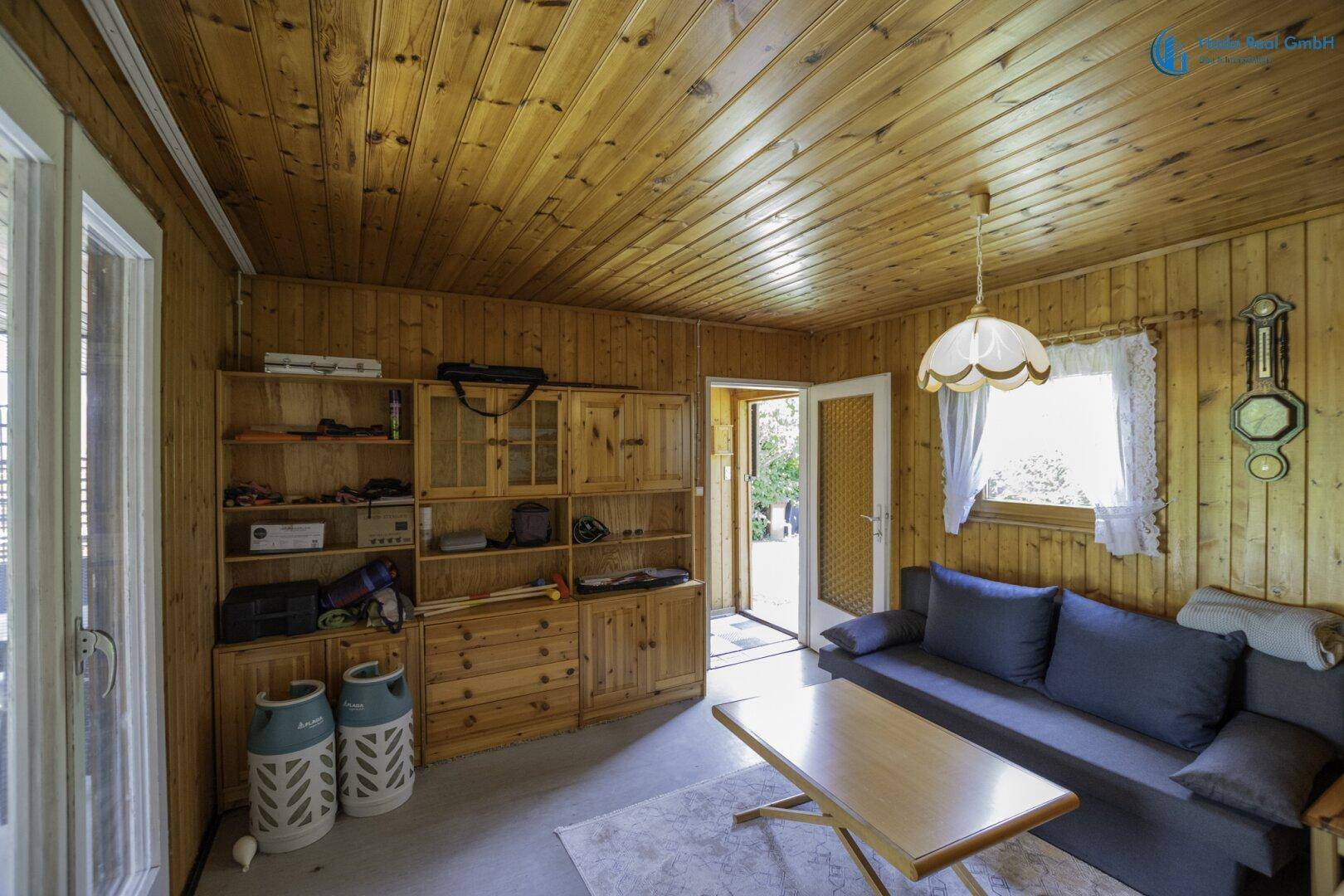 Gemütliches Wohnzimmer mit Holzvertäfelung, Schrankwand und Sofa, ideal zum Entspannen.