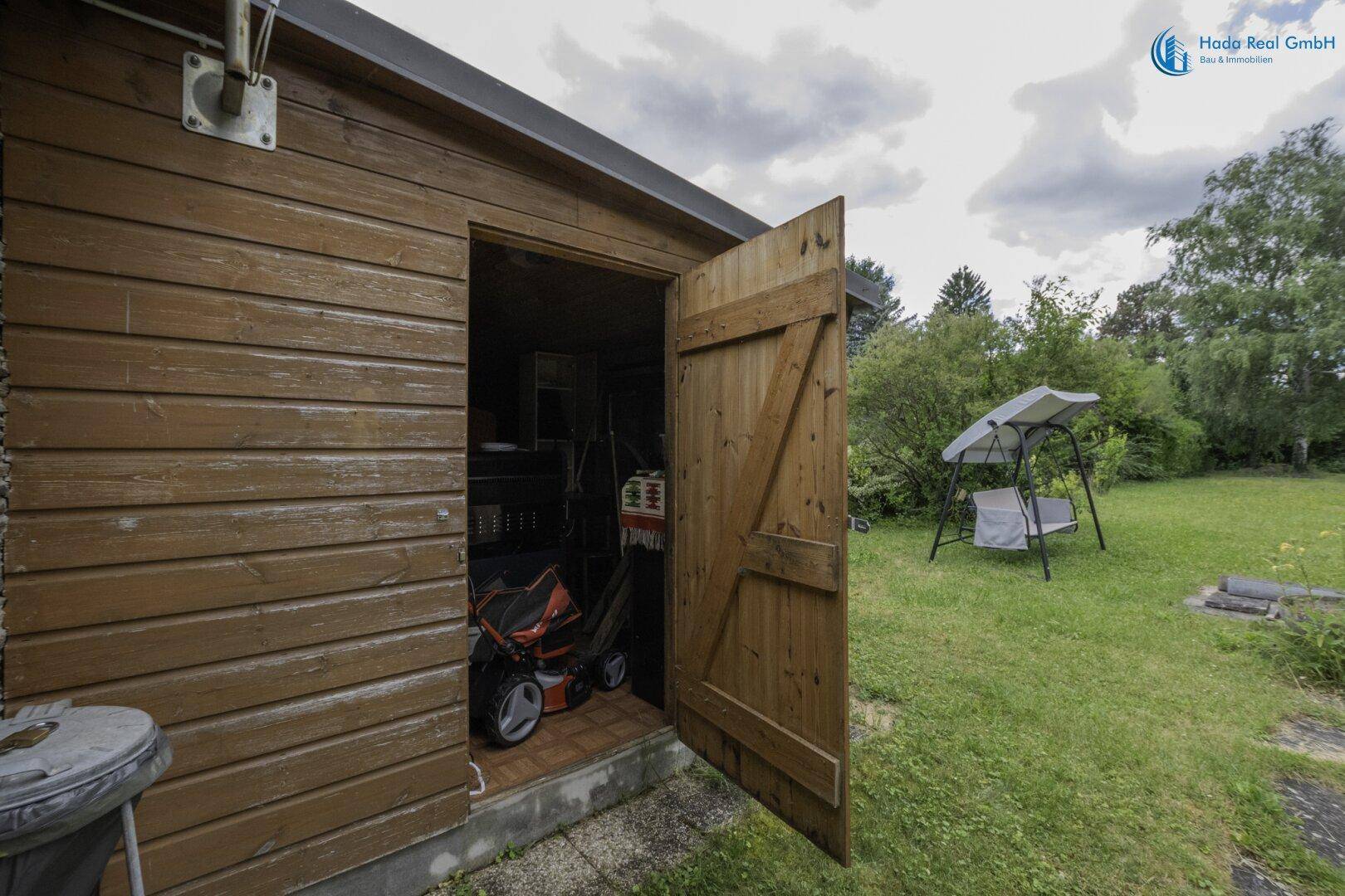 Offener Holzschuppen im Garten, genutzt zur Aufbewahrung von Gartengeräten und Werkzeugen.